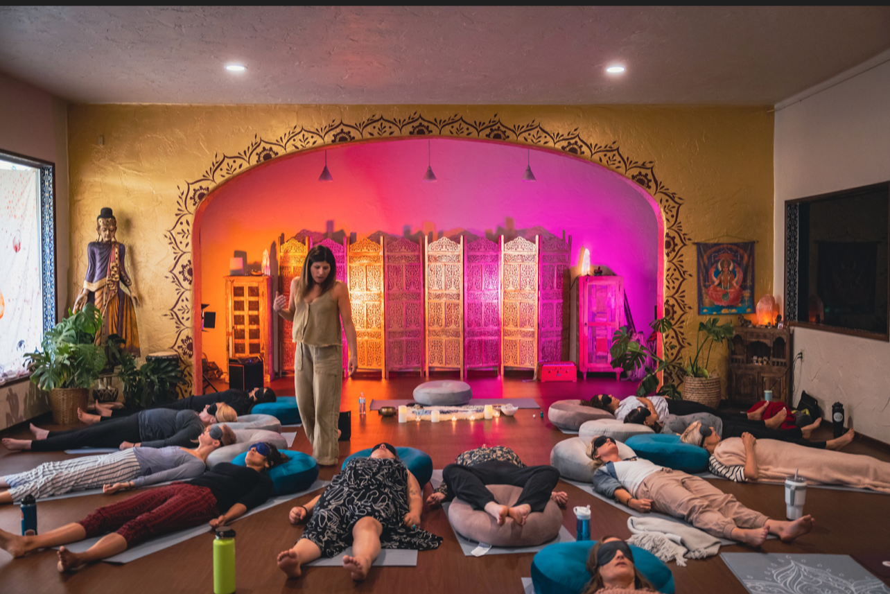 Women participating in a group breathwork and meditation ceremony at Highest Source Healing’s Orange County studio, surrounded by plants, candlelight, and sacred décor