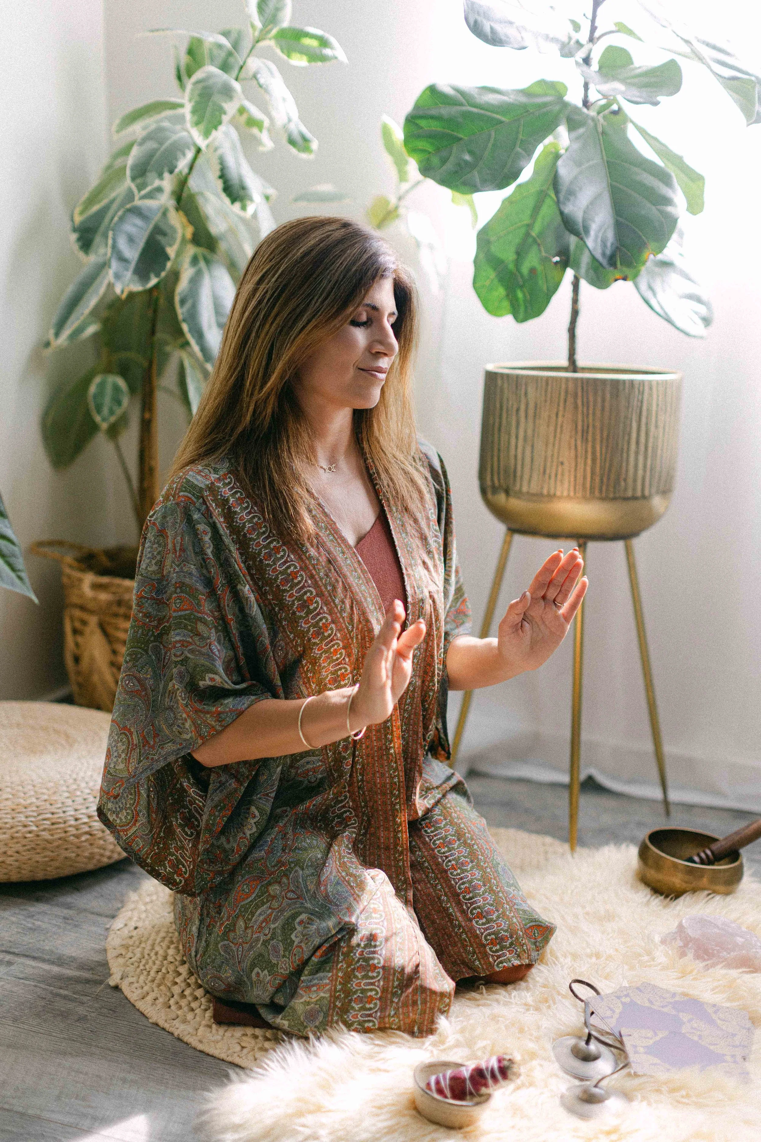 Jennifer practicing breathwork and ritual meditation surrounded by healing tools
