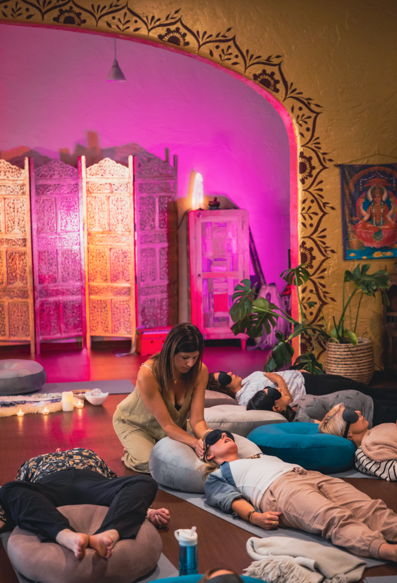 Women in deep relaxation during a breathwork and Reiki healing session, lying on mats with eye masks in a softly lit ceremony space