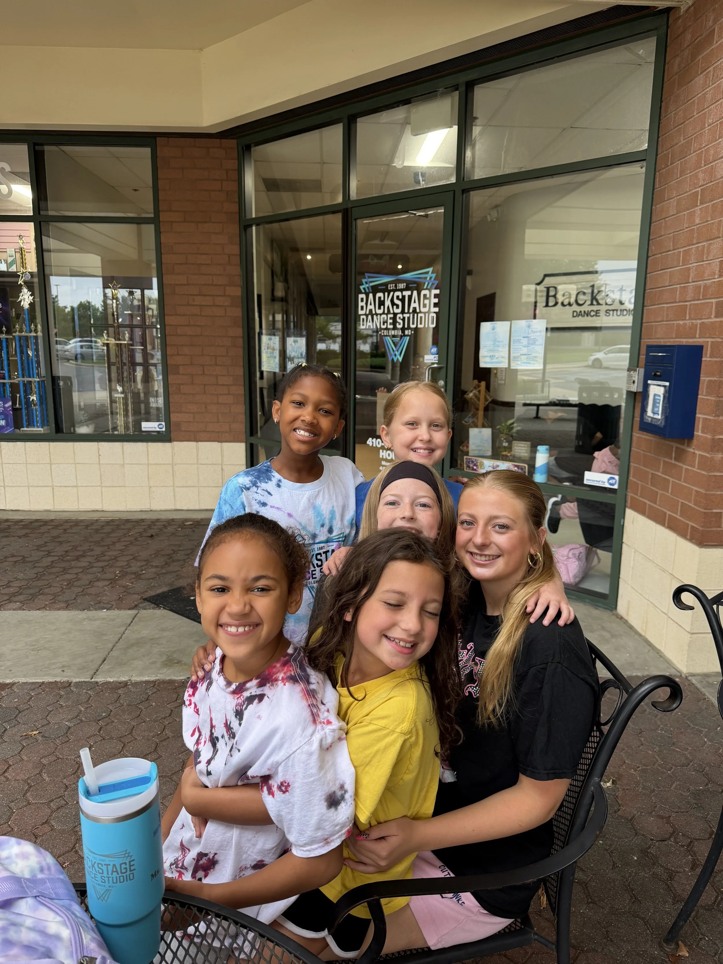 Summer dance camp students laughing and having fun outside with their teacher at Backstage Dance Studio.