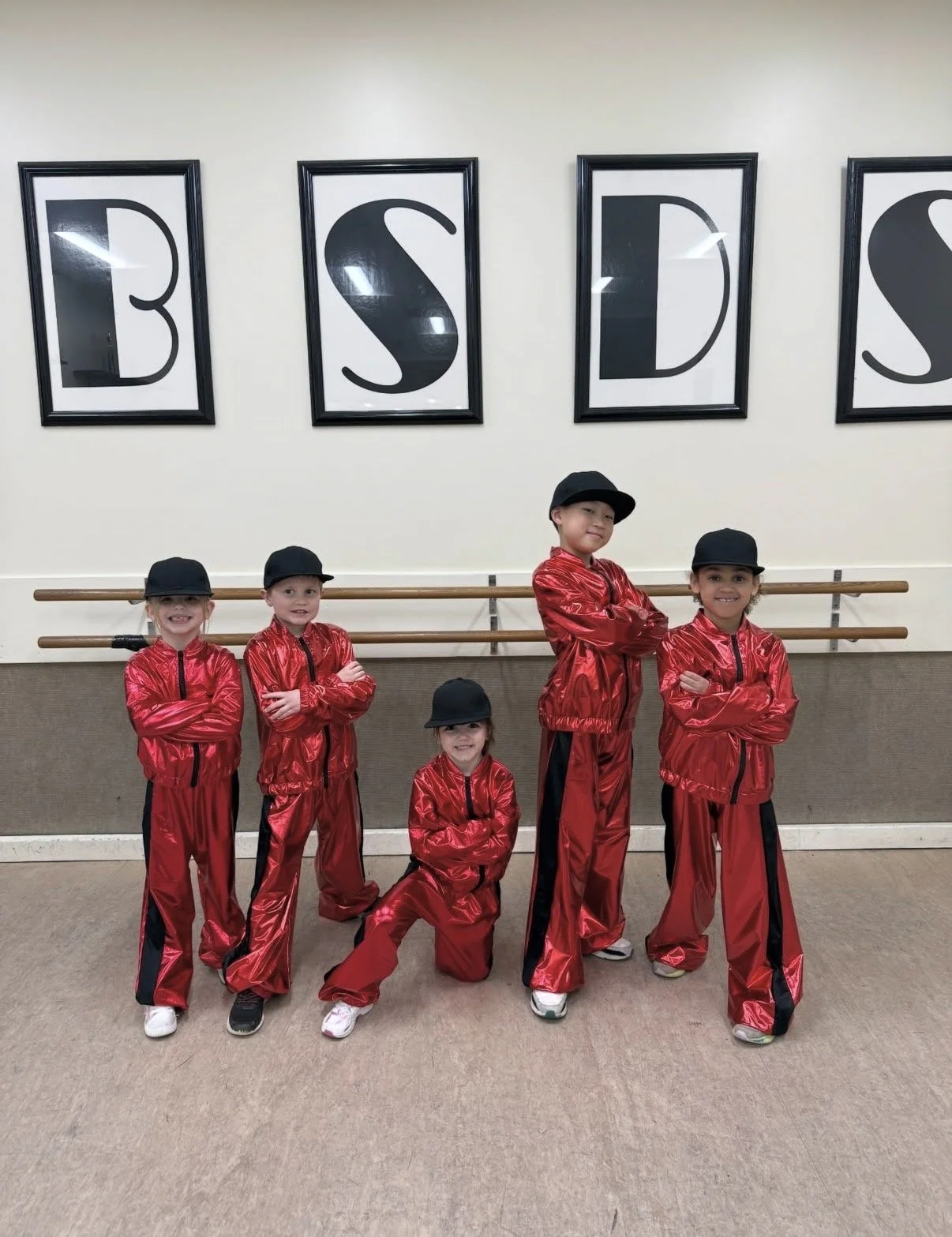 Hip hop dancers posing together in the classroom after receiving their recital costumes at Backstage Dance Studio.