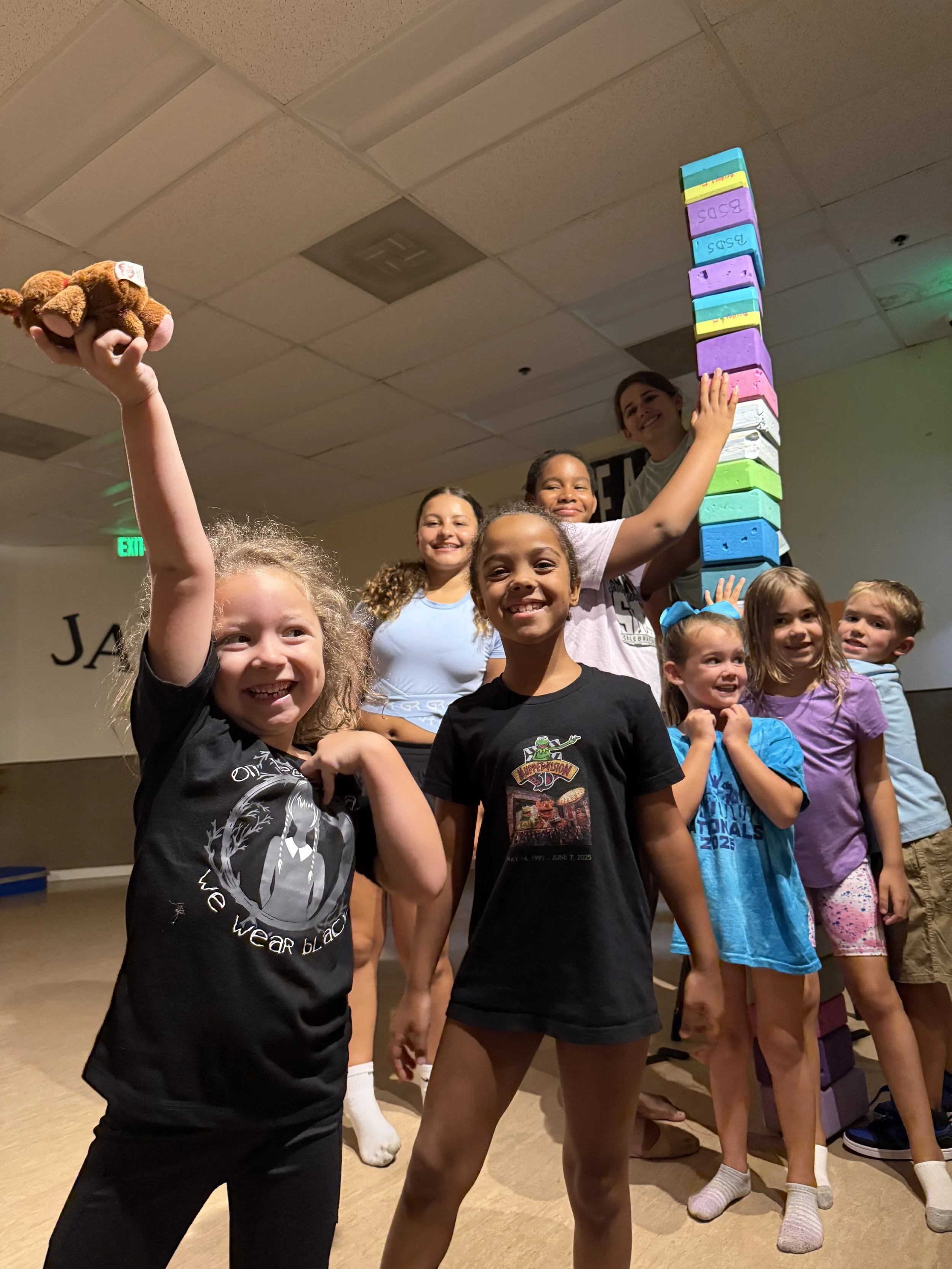 Backstage Dance Studio dancers smiling together after stacking yoga blocks during dance class.