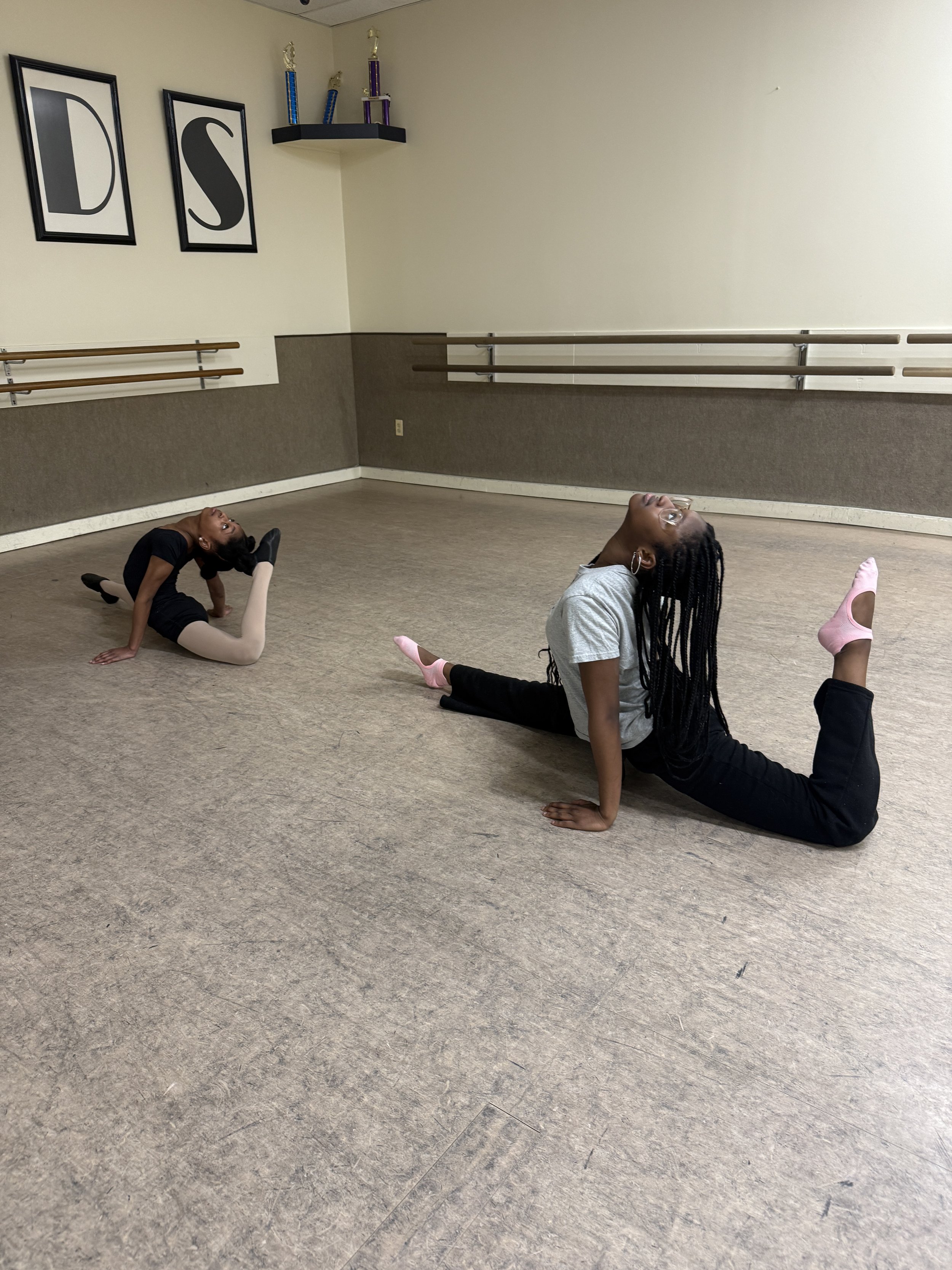 Backstage Dance Studio dancers practicing flexibility and splits during dance class.