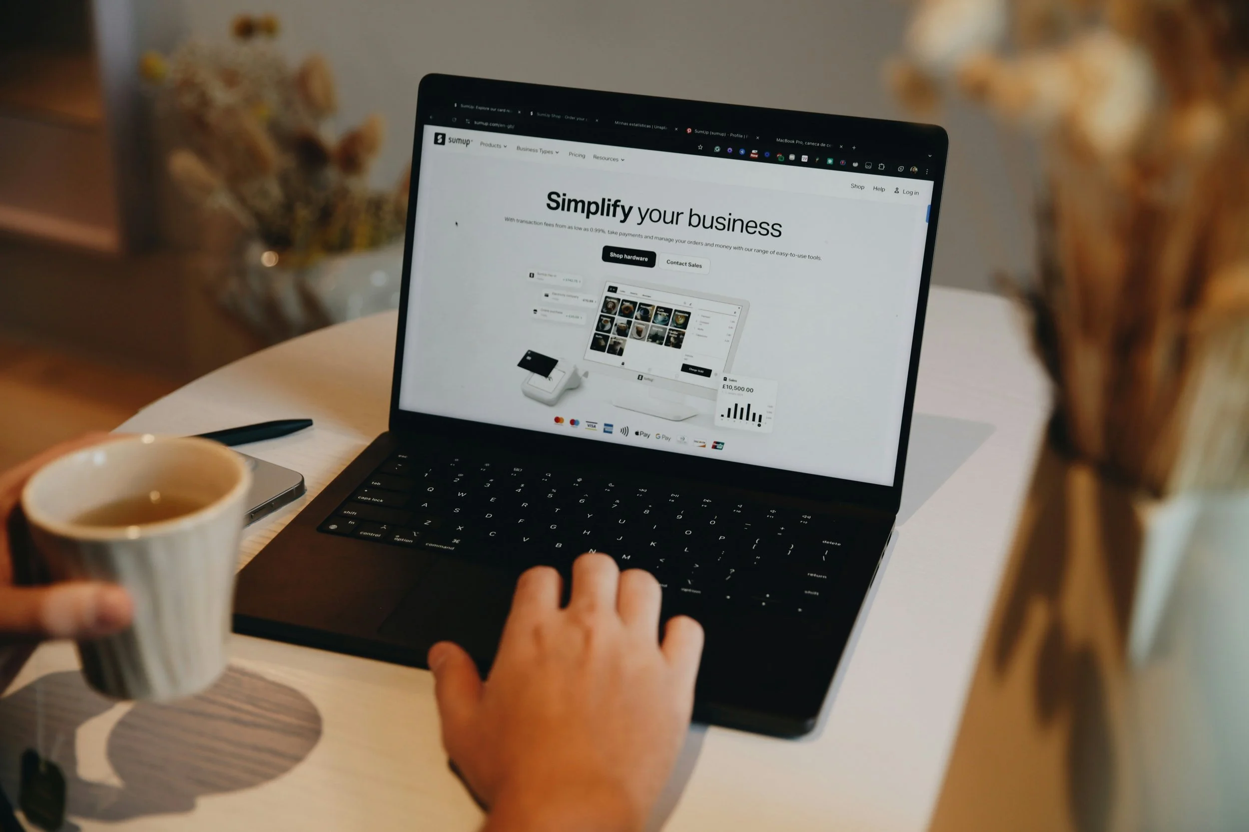Person reviewing a business management dashboard on a laptop while holding a cup of coffee