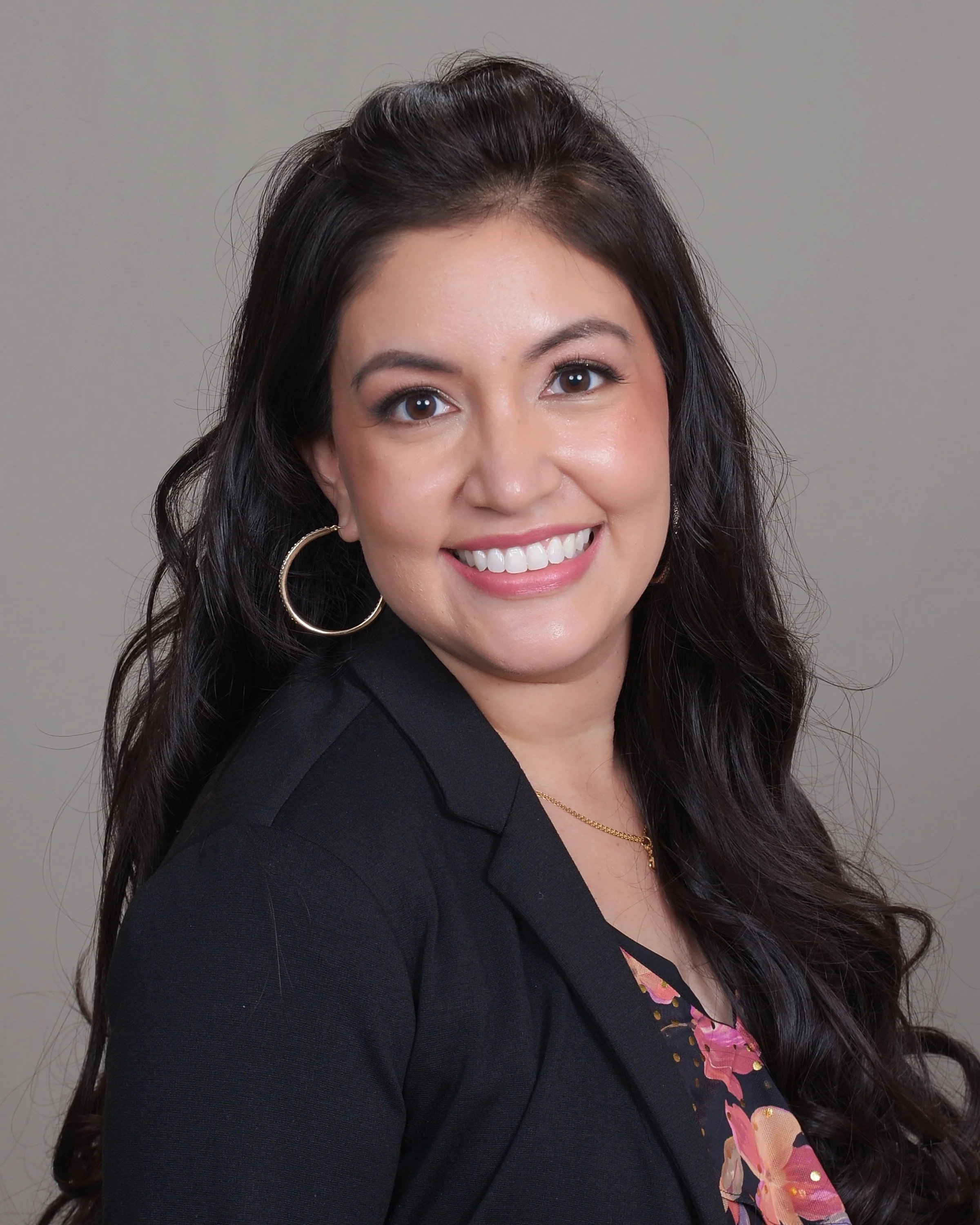 Portrait of a smiling Latina with long wavy brown hair and gold hoop earring