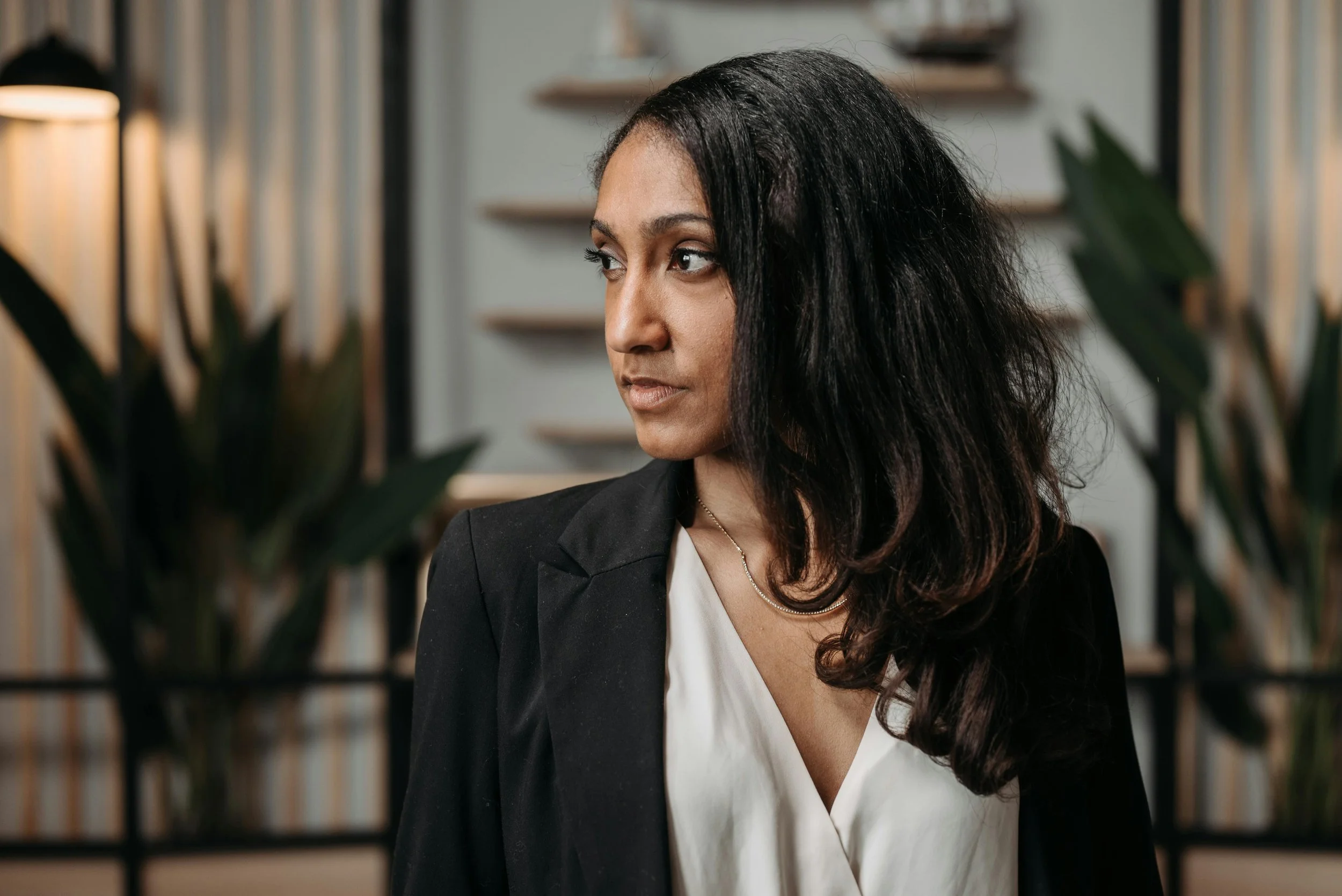 South Asian Indian American woman executive professional in suit in her corner office.
