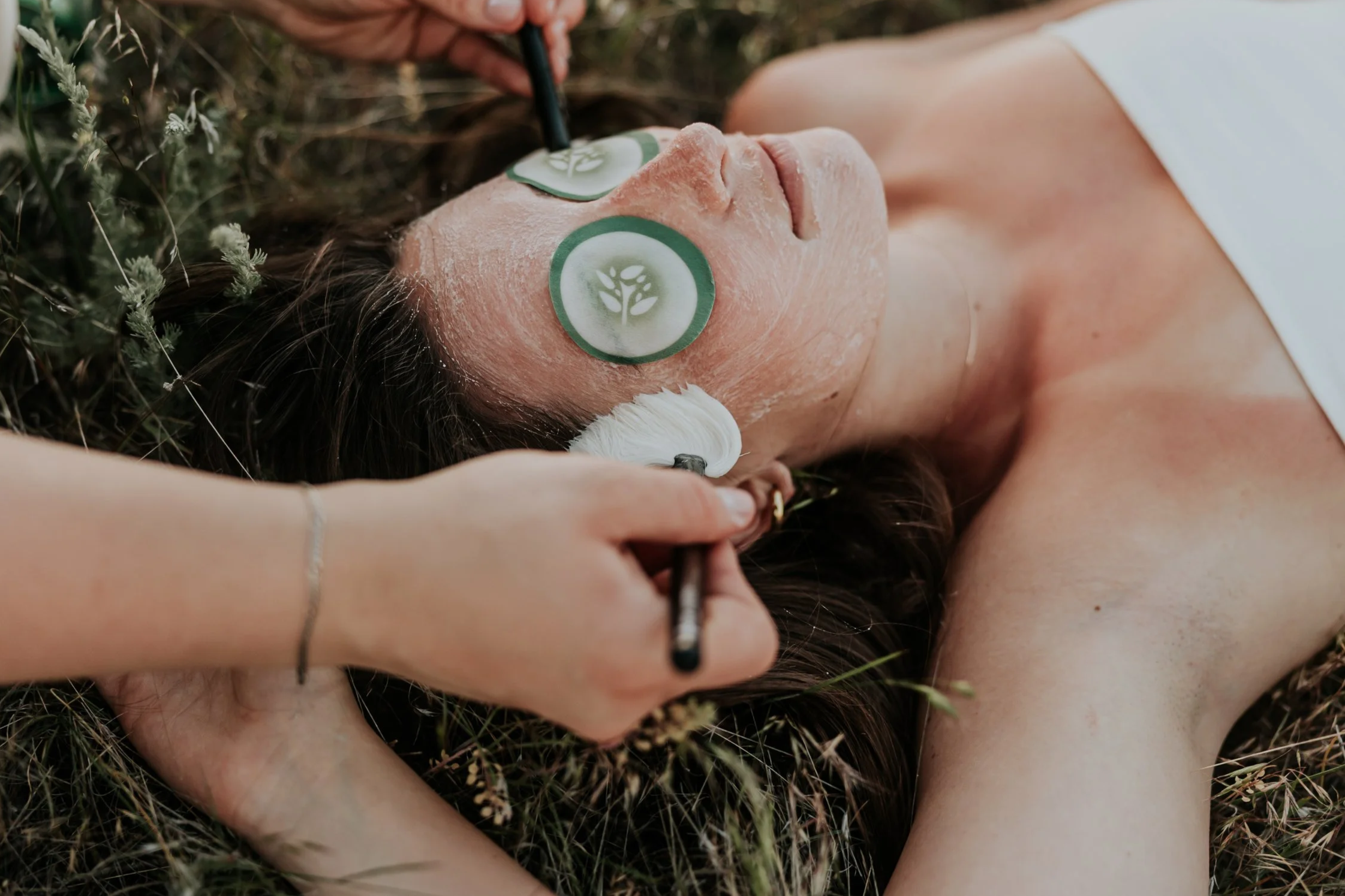 A woman getting a facial with a green mask applied to her face at a spa or skincare clinic.