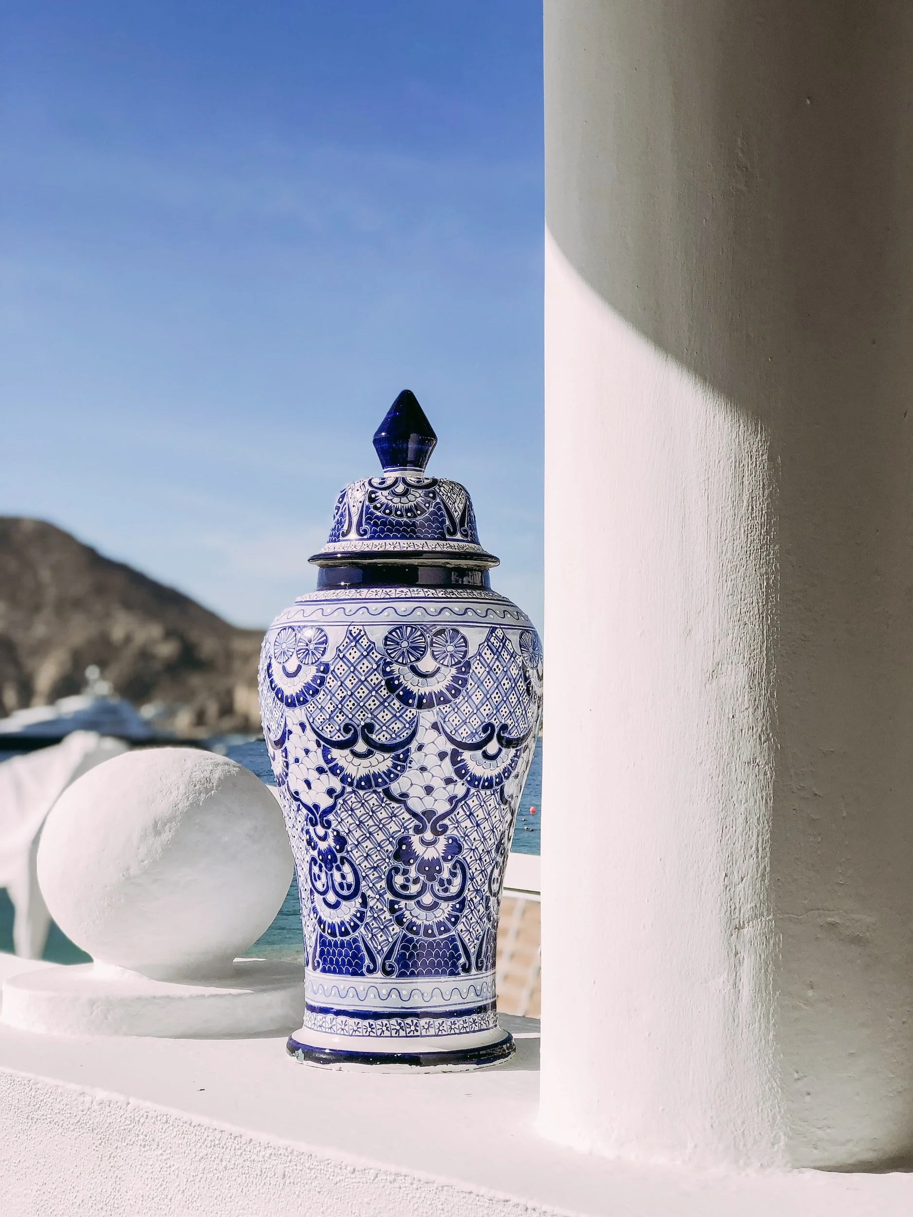 Blue and white ornate ceramic crematory urn on white outdoor ledge
