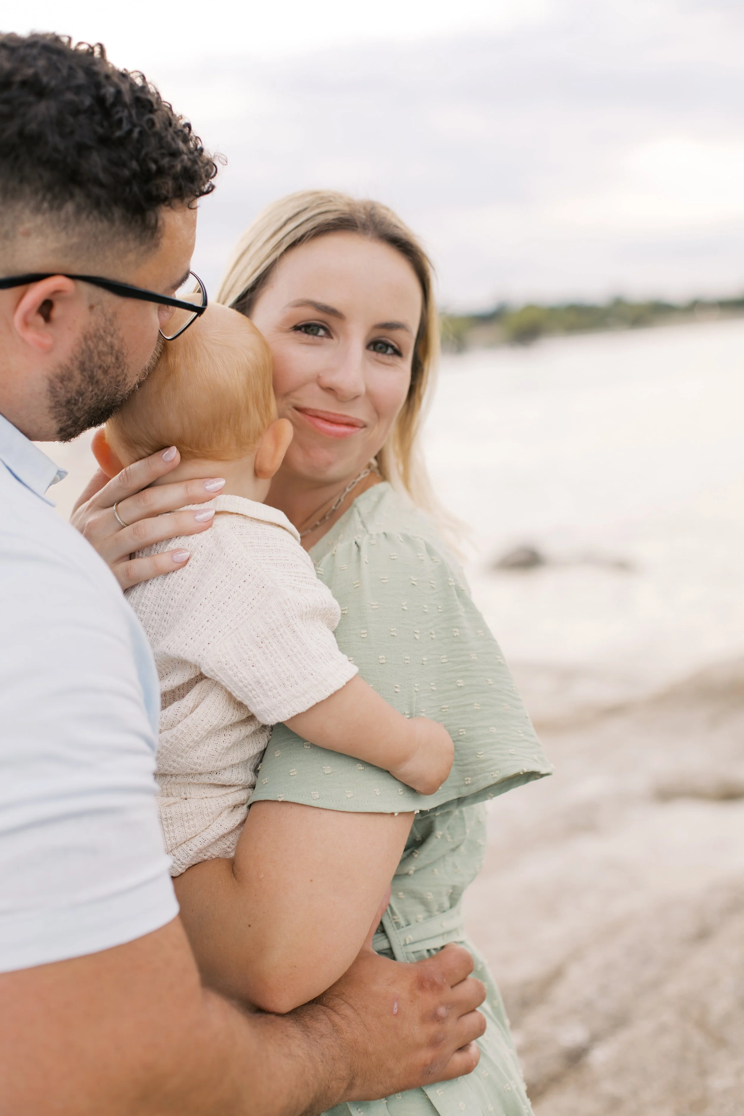 mom and baby and dad kissing baby