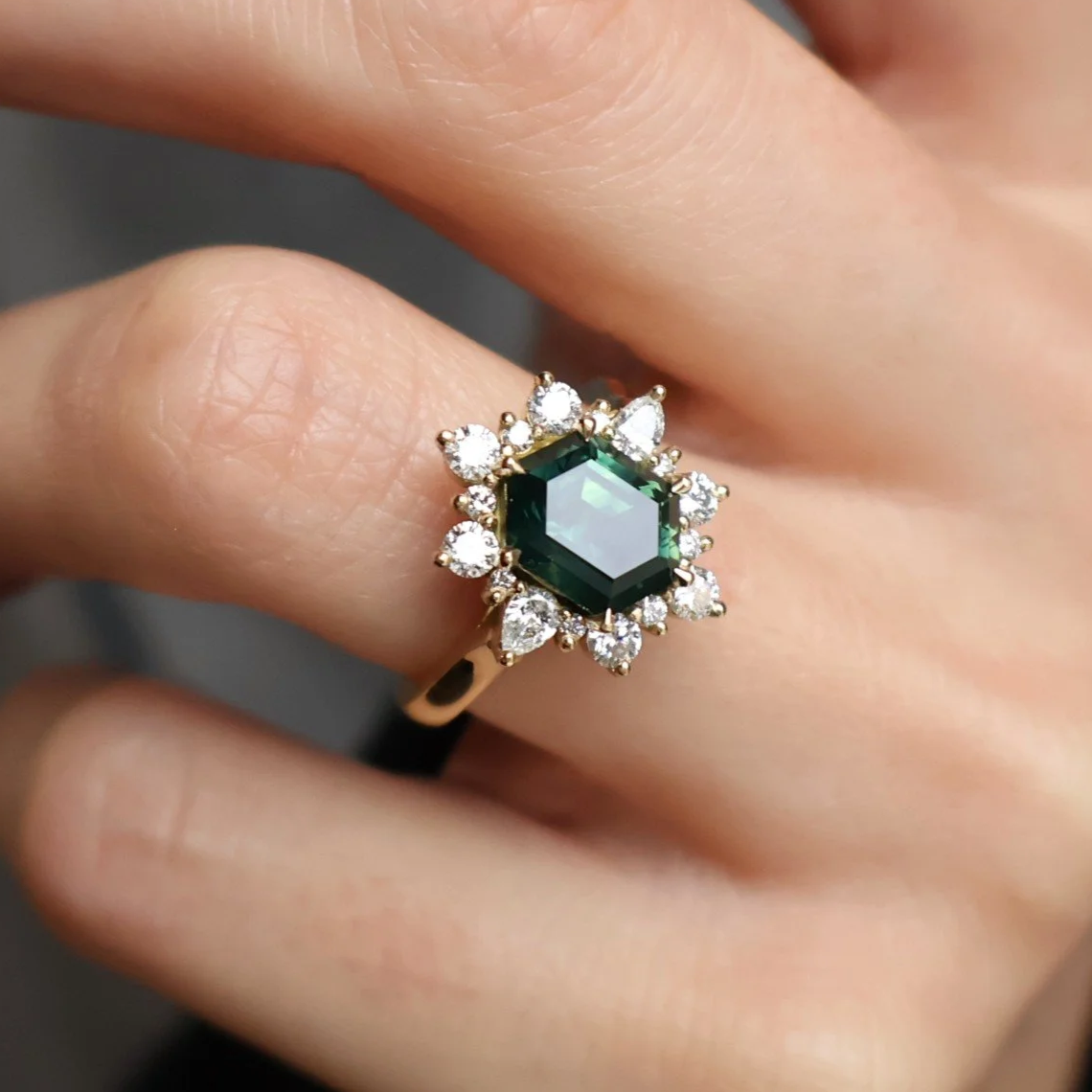 Hexagonal green sapphire with a round diamond halo set into an 18ct yellow gold ring