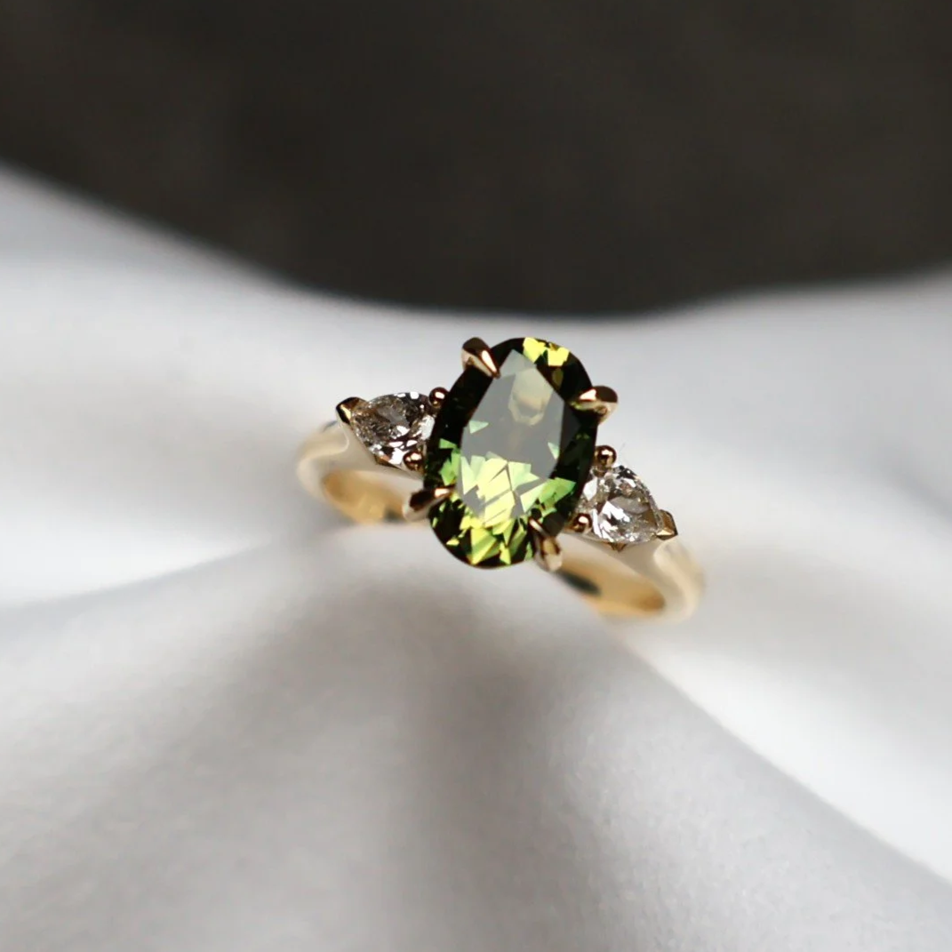 Oval green sapphire and pear diamond three stone ring