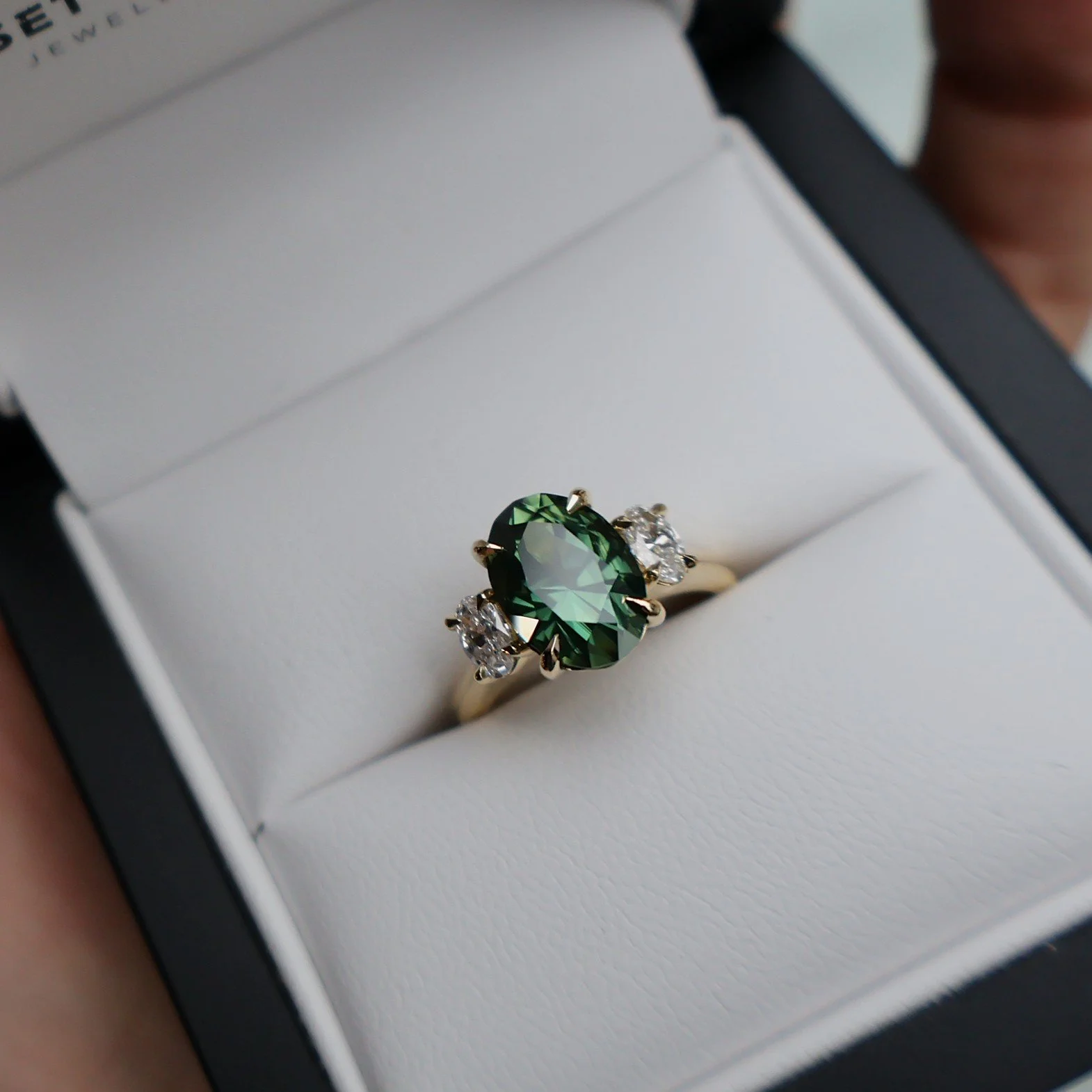 Oval green sapphire and oval diamond three stone ring in a box Issac.JPG