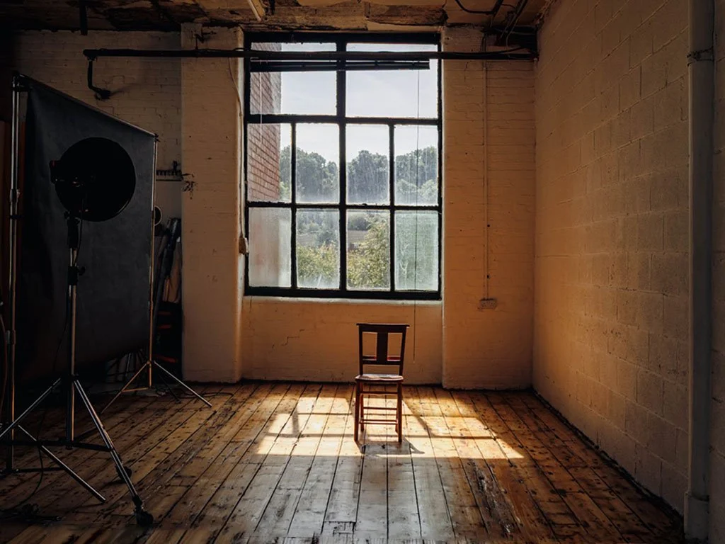 Empty wooden chair and photography equipment prepared for a Victorious Voices portrait session. Learn how to take part.