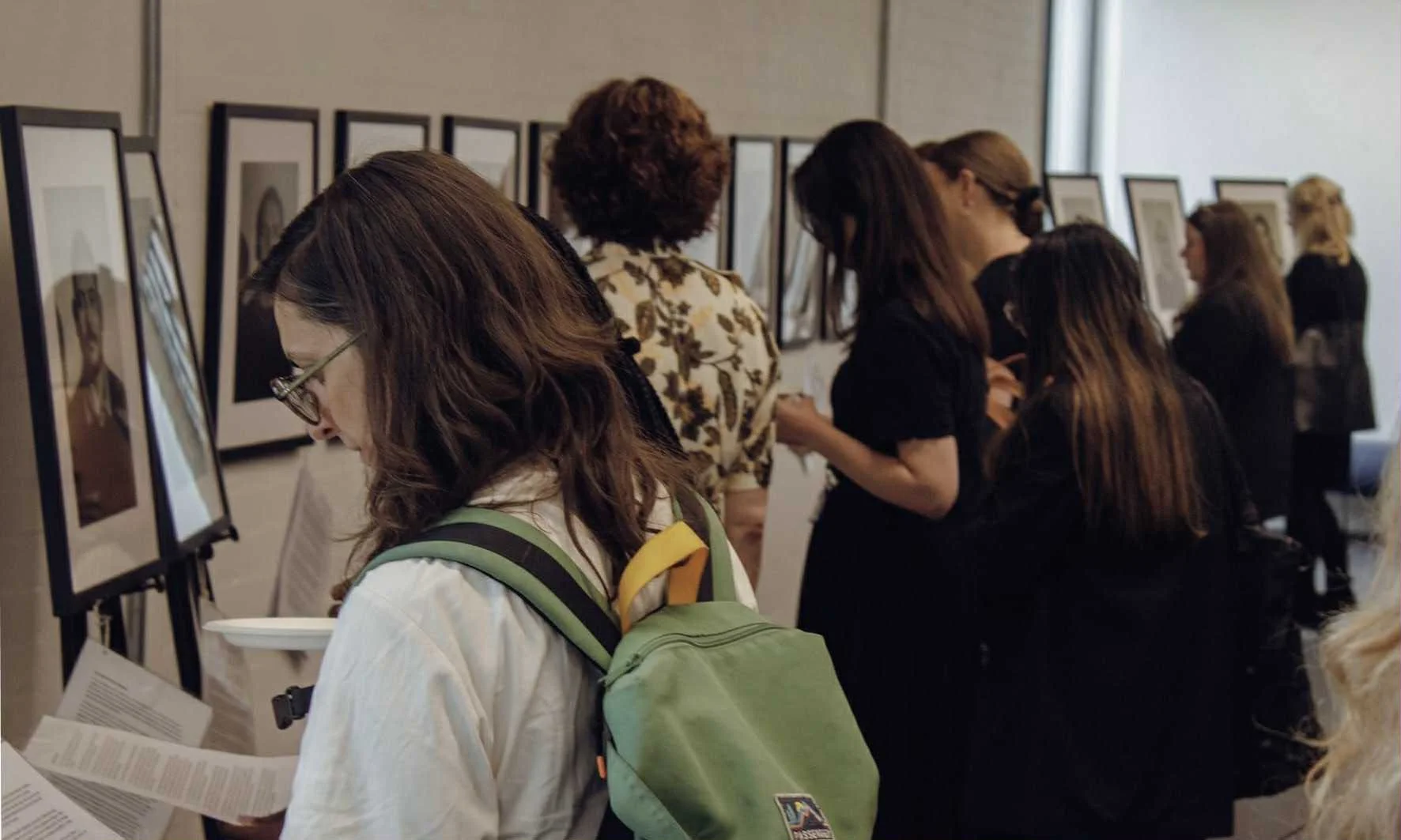 Visitors viewing framed Victorious Voices portraits at a public exhibition. Read about the project’s impact.