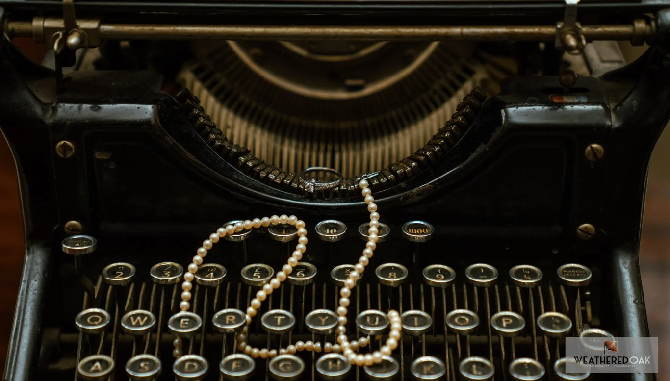Close-up of a vintage typewriter with a string of pearls draped over the keys.