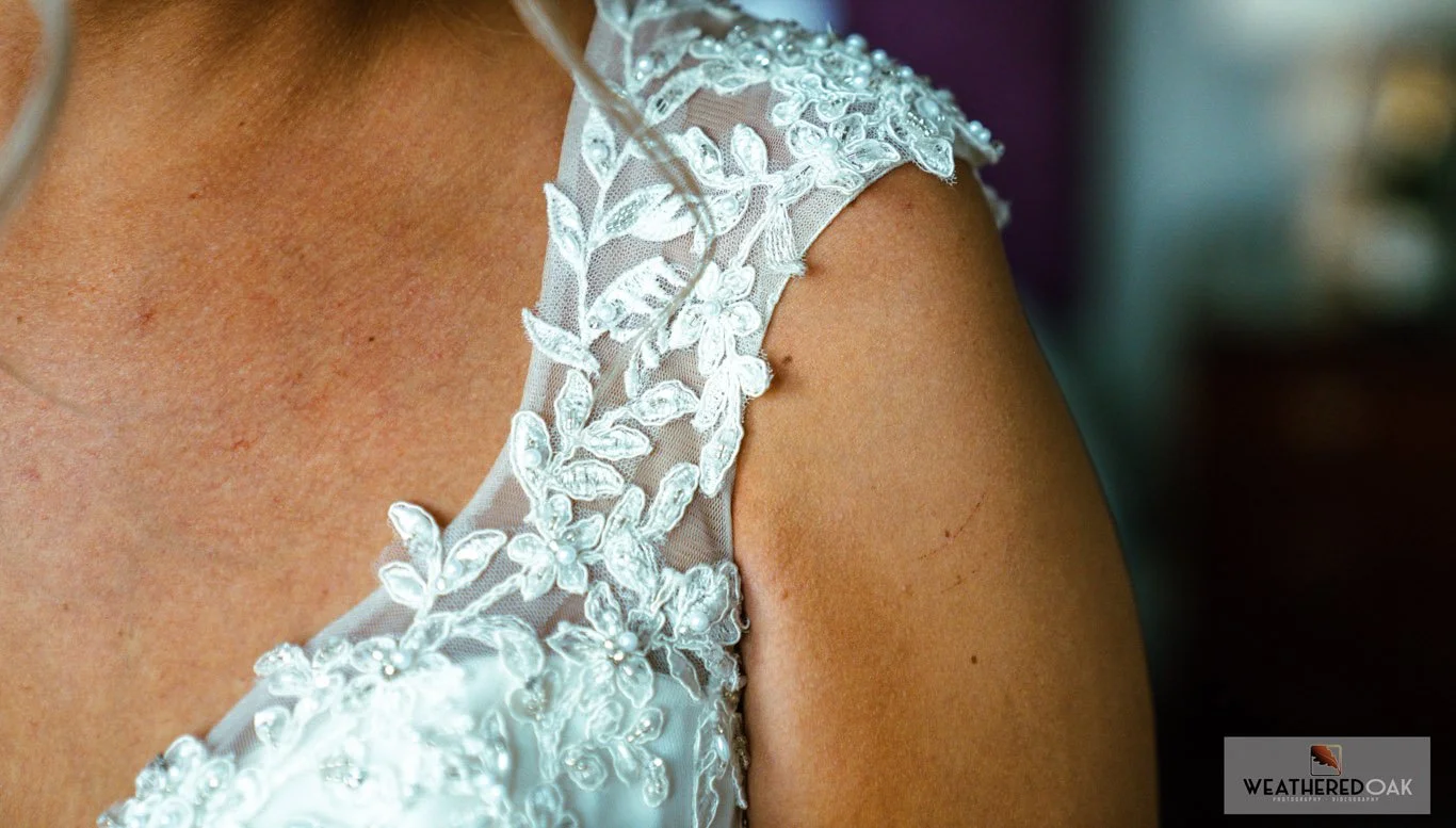 Close-up of a white lace and beaded wedding dress shoulder detail.
