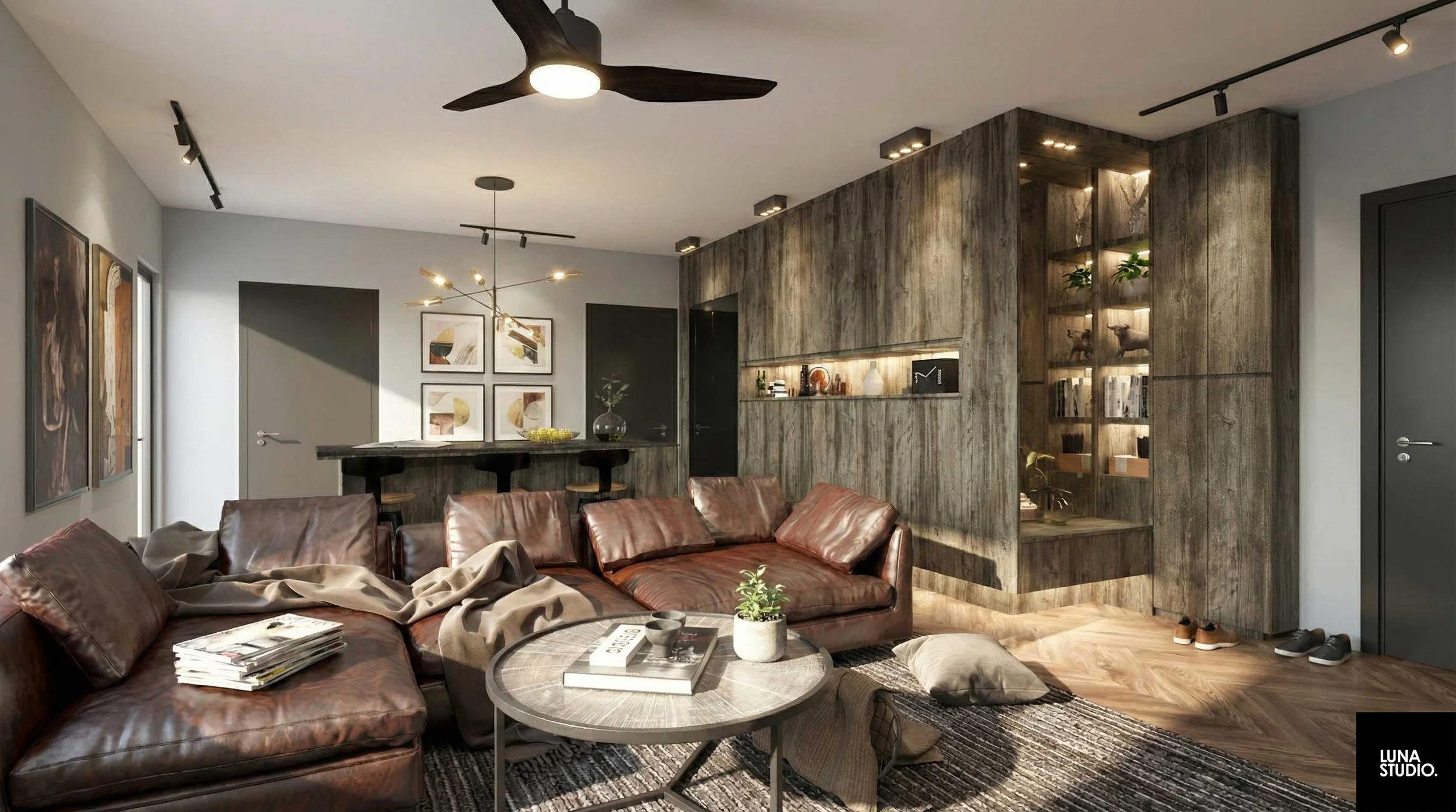 Modern living room with a leather sectional sofa, a round coffee table with a plant on top, and a built-in wooden wall with display shelves. Artwork hangs on the light gray walls, and a ceiling fan is visible. There is a bar area with a black bar and stools in the background, and a sliding glass door on the left. Shoes are placed near the door, and a patterned rug is under the coffee table.