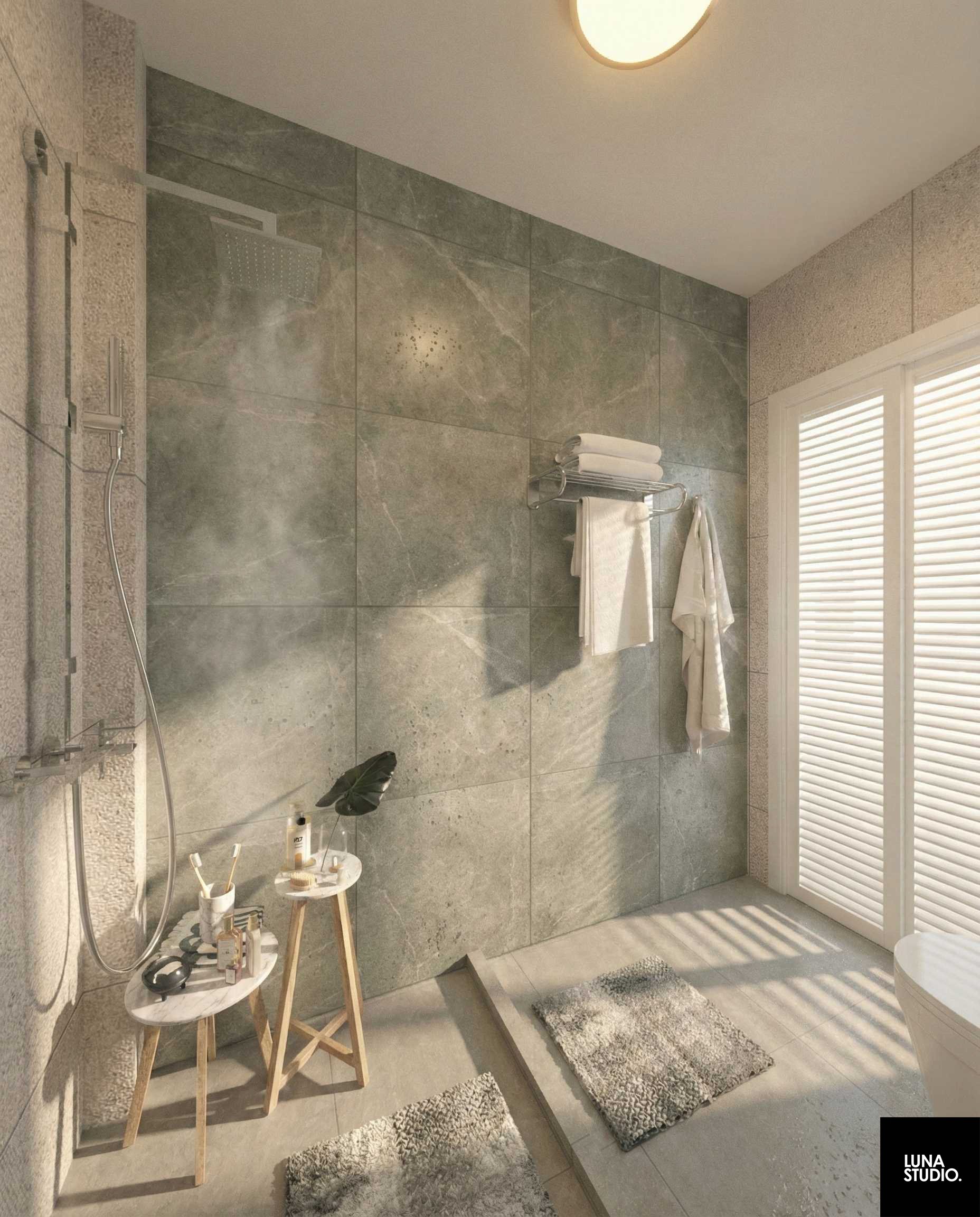 A modern bathroom with large grey tiled walls, a rain showerhead, a towel rack with towels, a small plant, and a window with blinds.