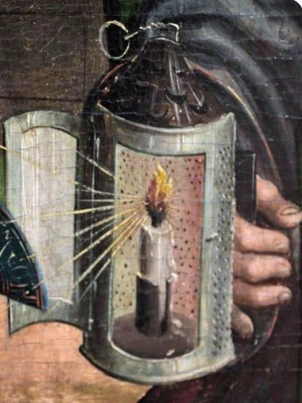 A medieval hand lantern with punched tin designs and a twisted wire hanging ring.