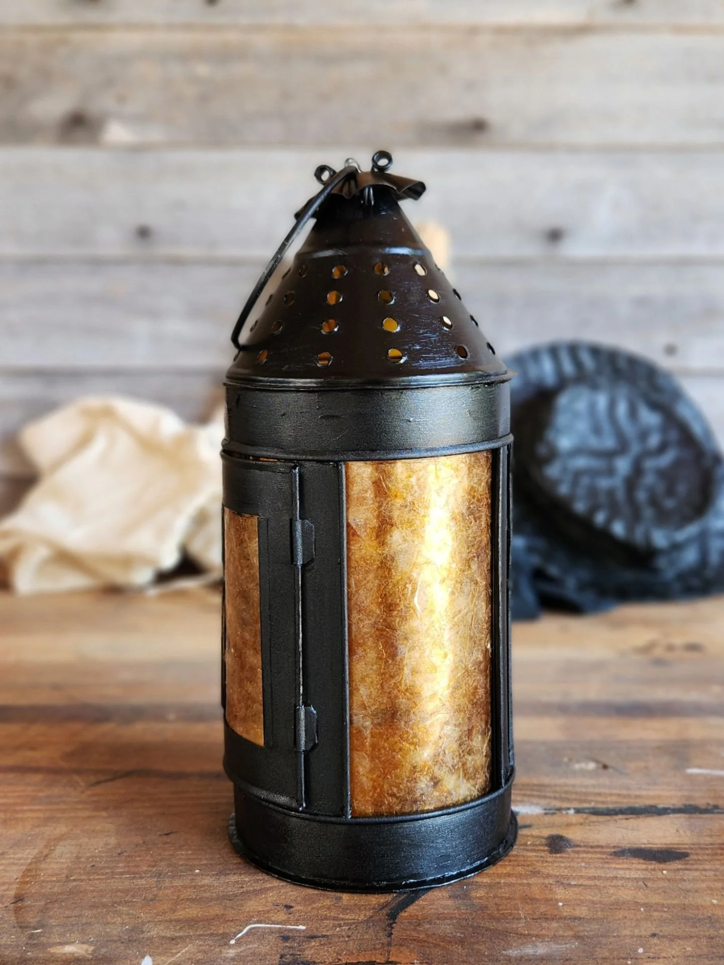 An early style hanging candle lantern with amber colored mica panes and black paint.
