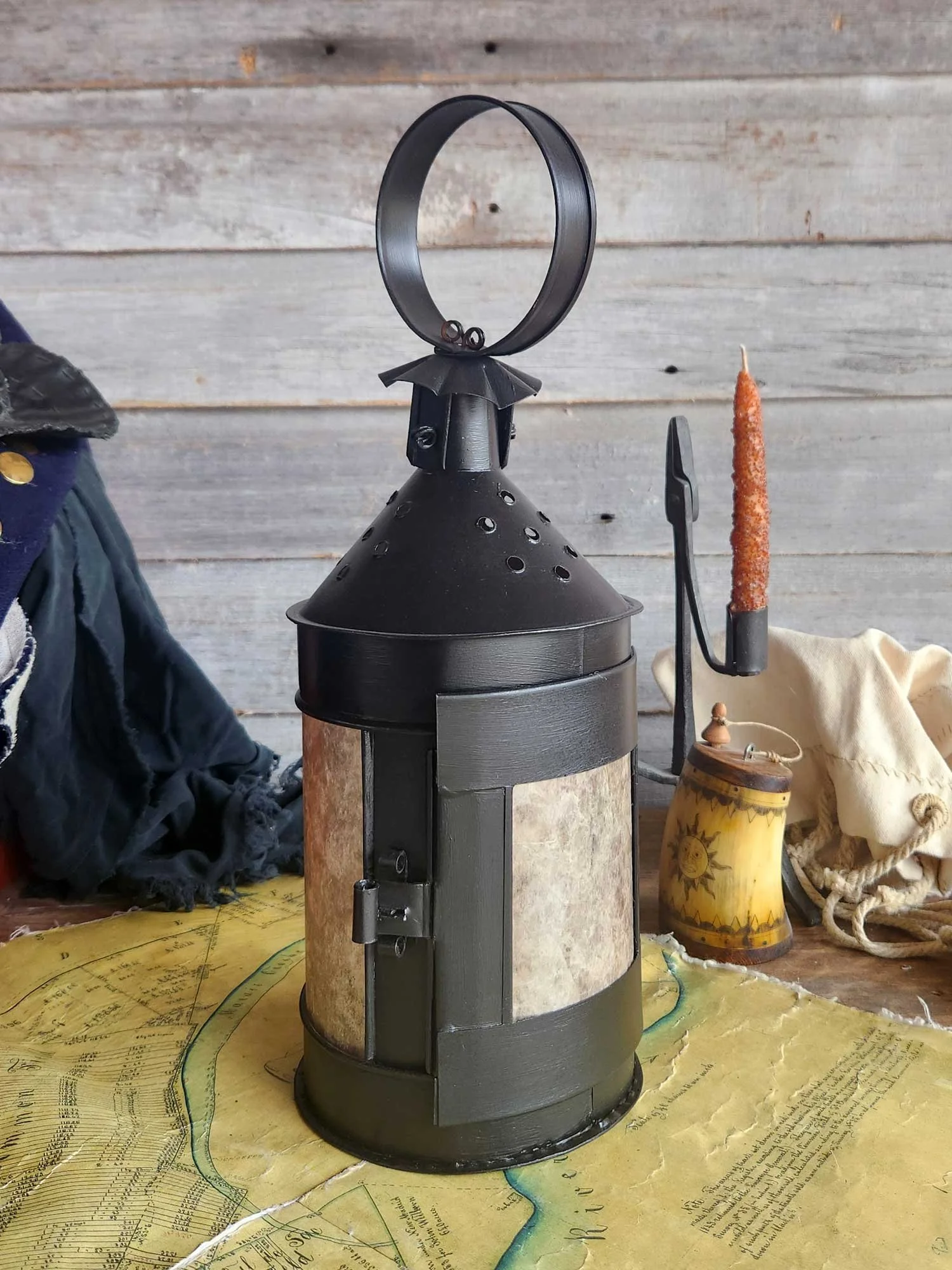 Medium sized round tin candle lantern with lite colored panes and black finish.