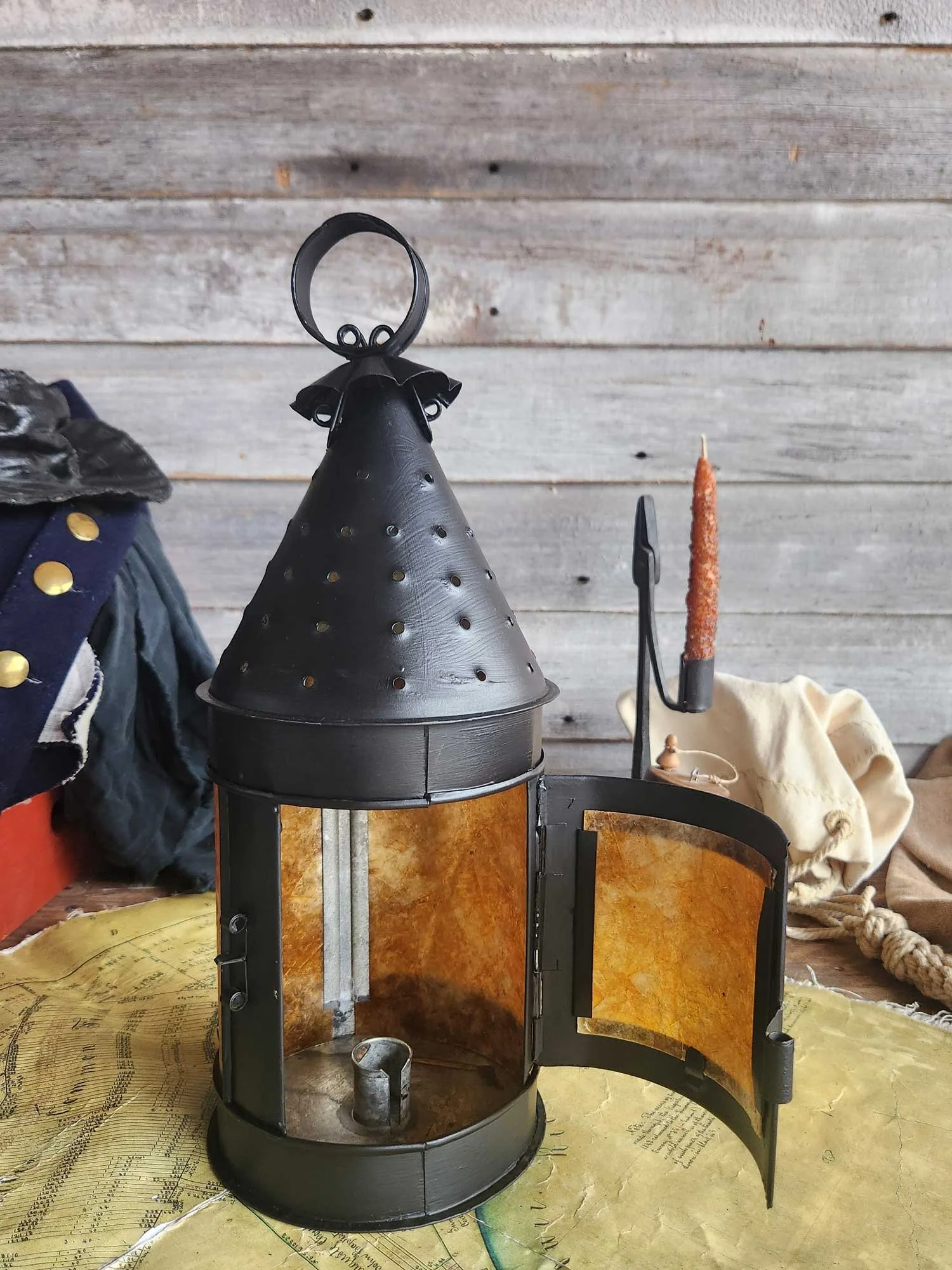 A round hanging tin candle lantern with 5 rows of small holes around the top cone.