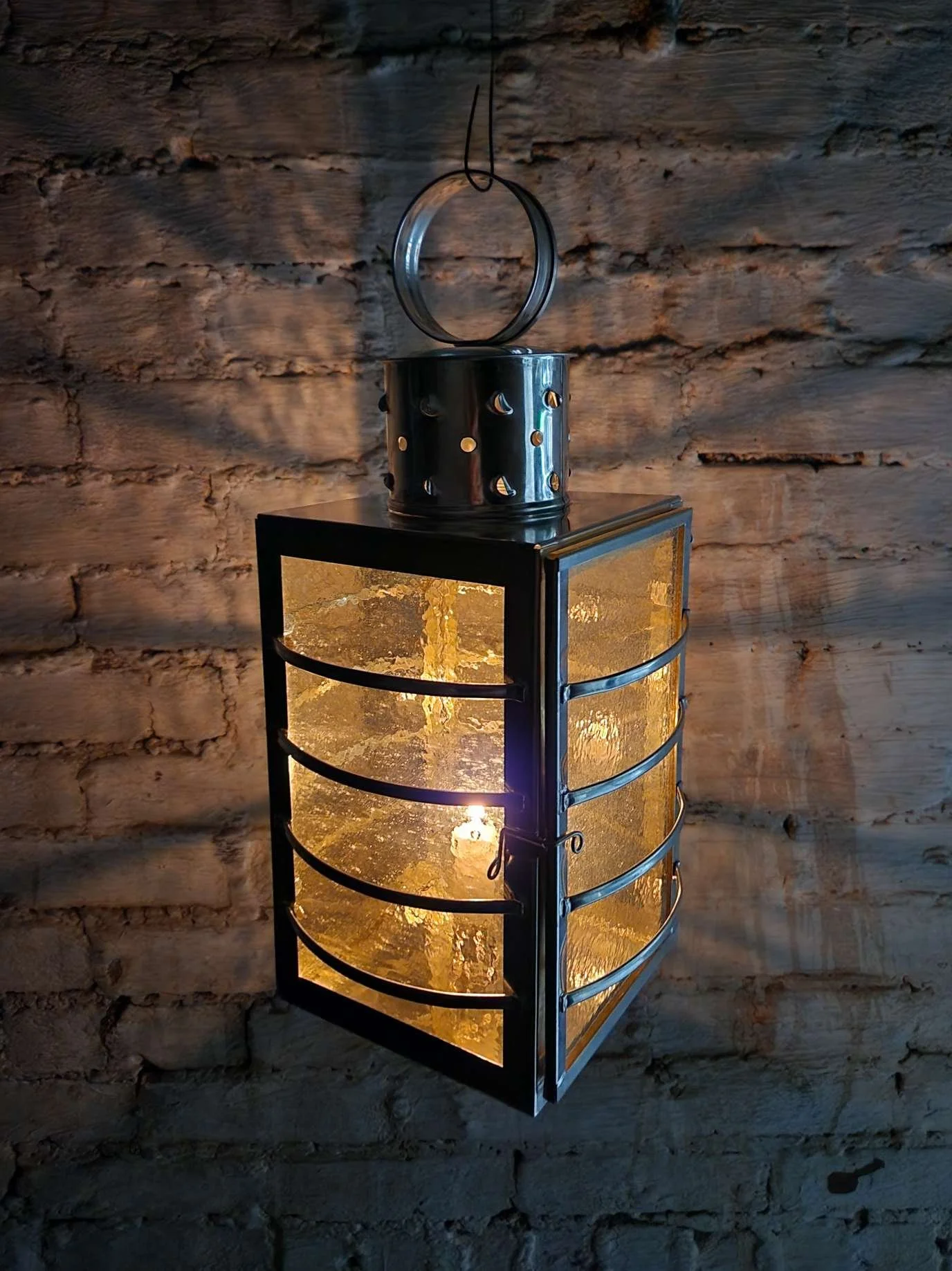 Round topped watch lantern lit by candle.