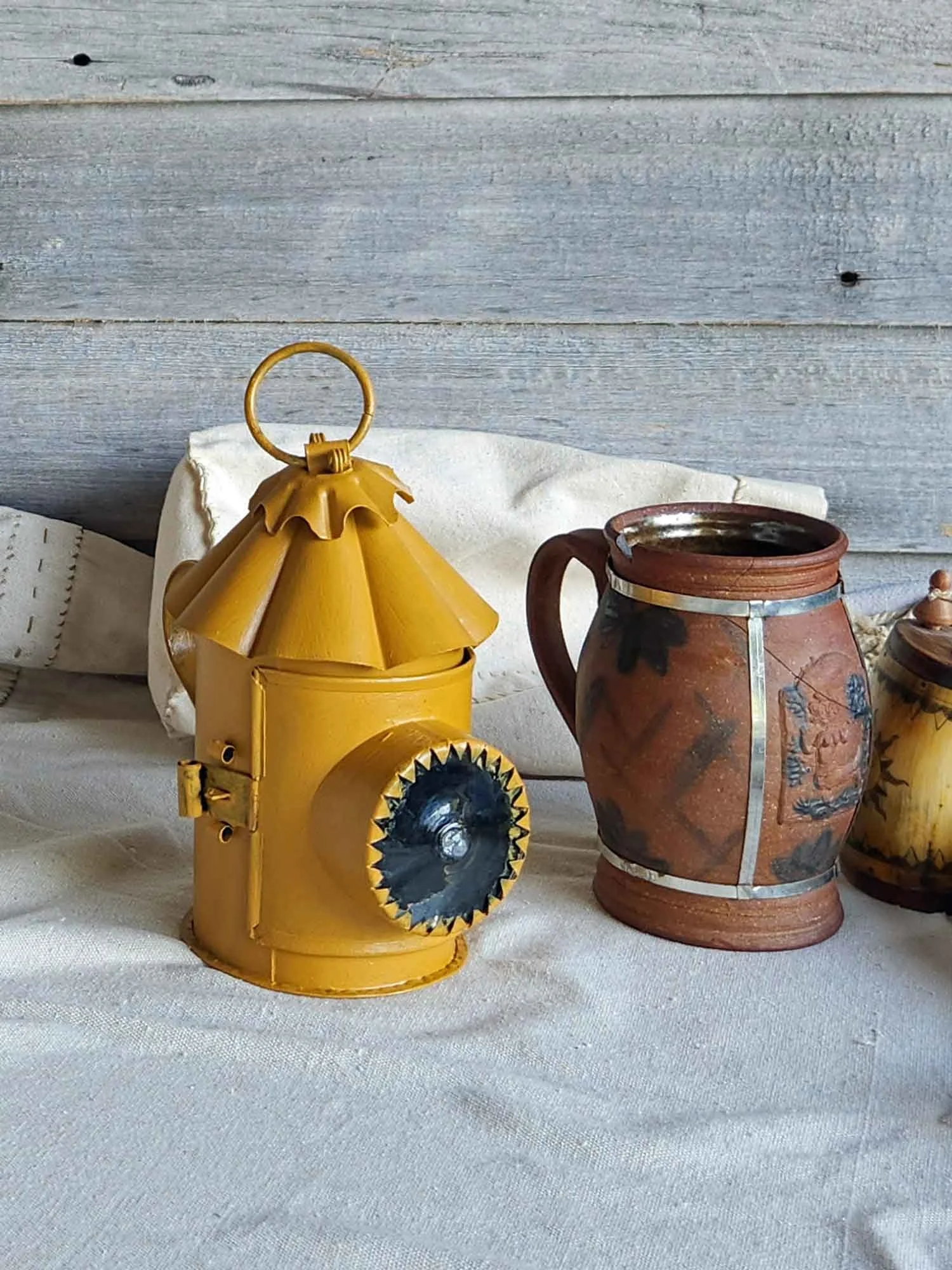 A mustard colored hand lantern with scalloped to and bulls-eye lens