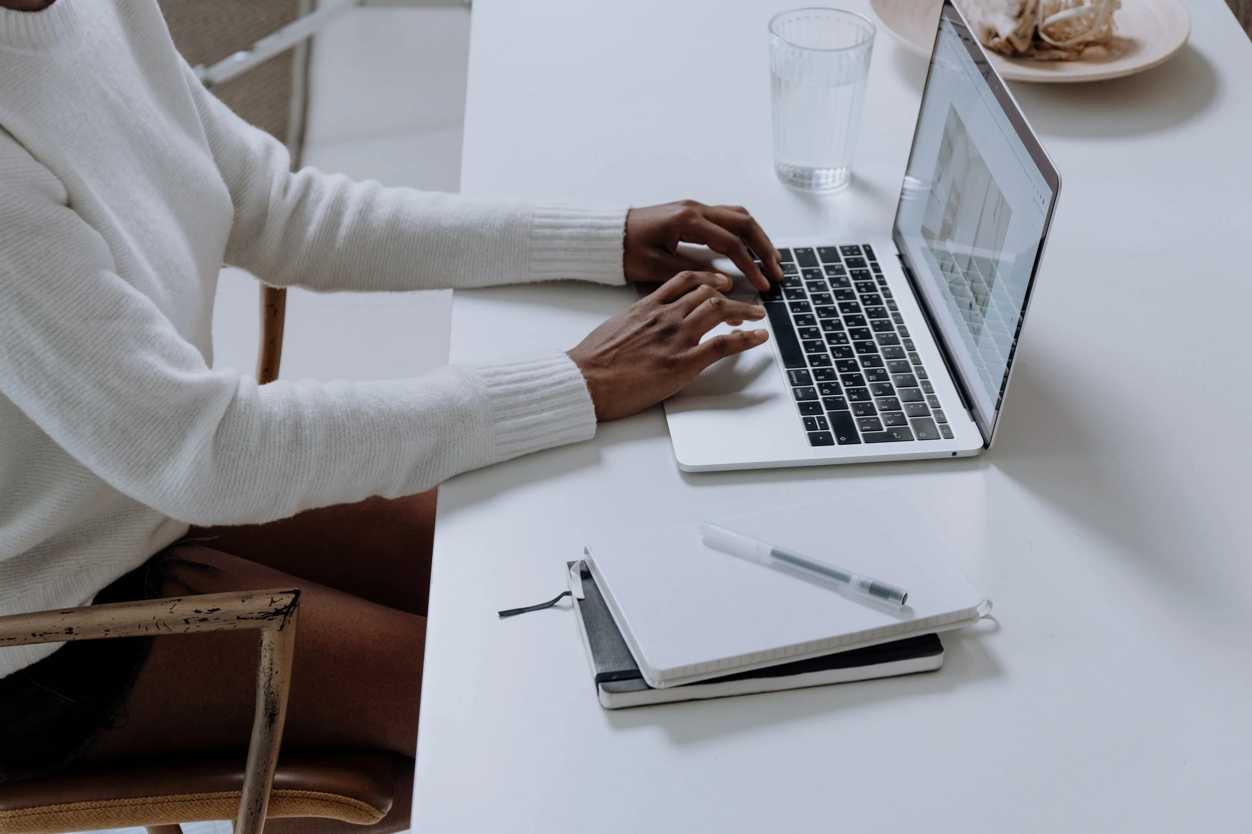 woman typing on laptop with notepad