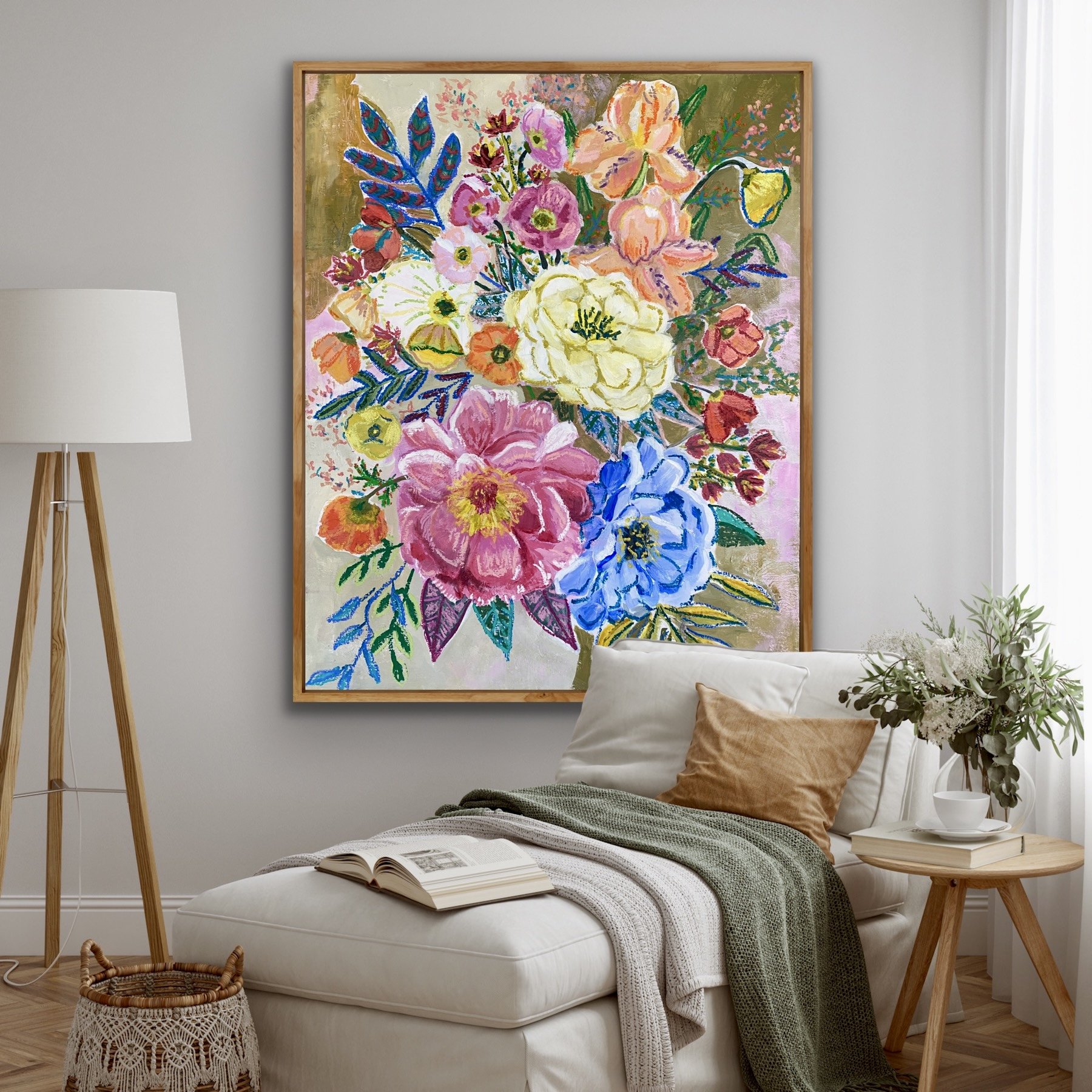 Bright, colorful floral painting hanging on a light gray wall in a cozy living room with a white chaise lounge, throw pillows, a green blanket, a side table with a potted plant, and a floor lamp.