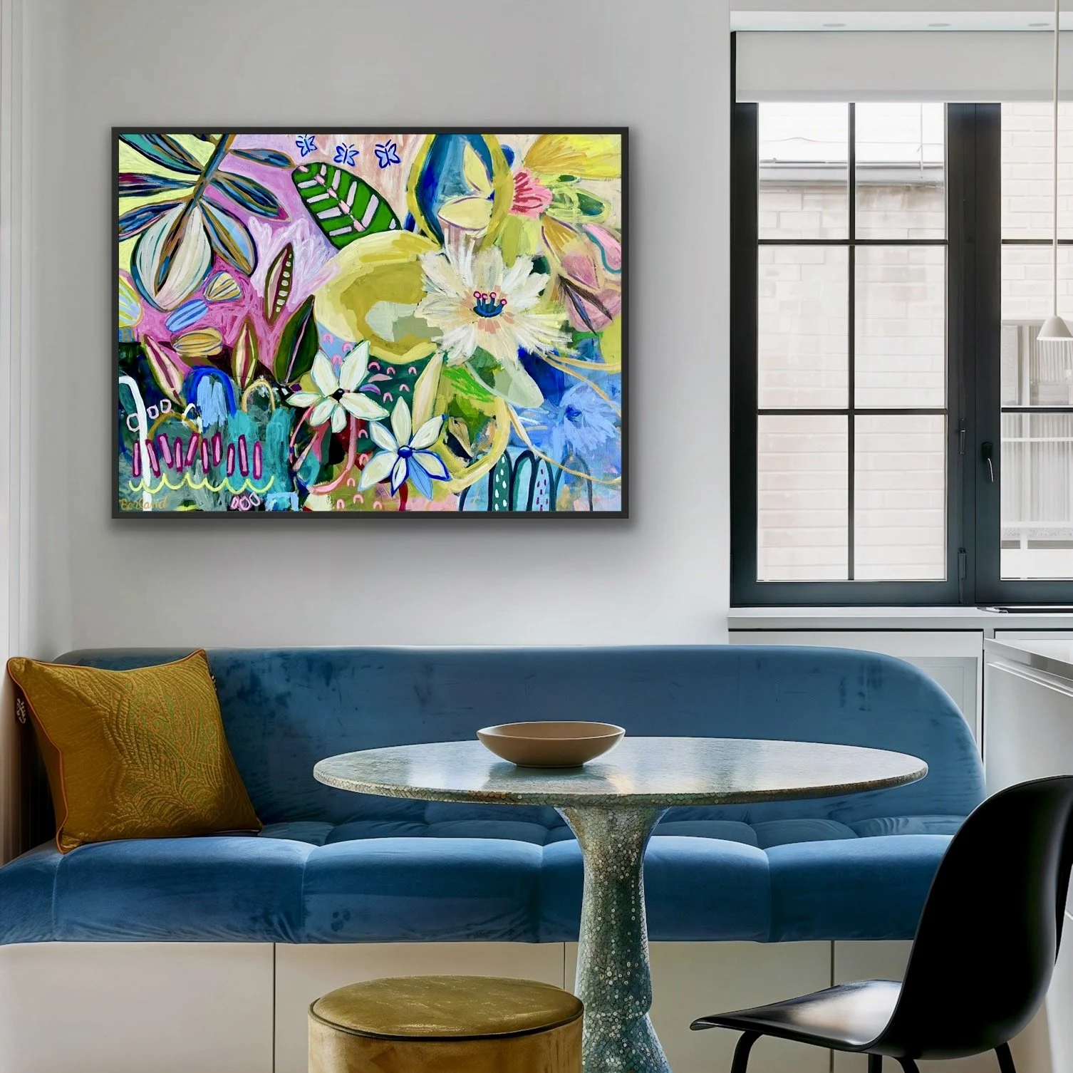 Modern living room with a blue velvet couch, a round table, black chair, and colorful abstract floral painting on the wall.