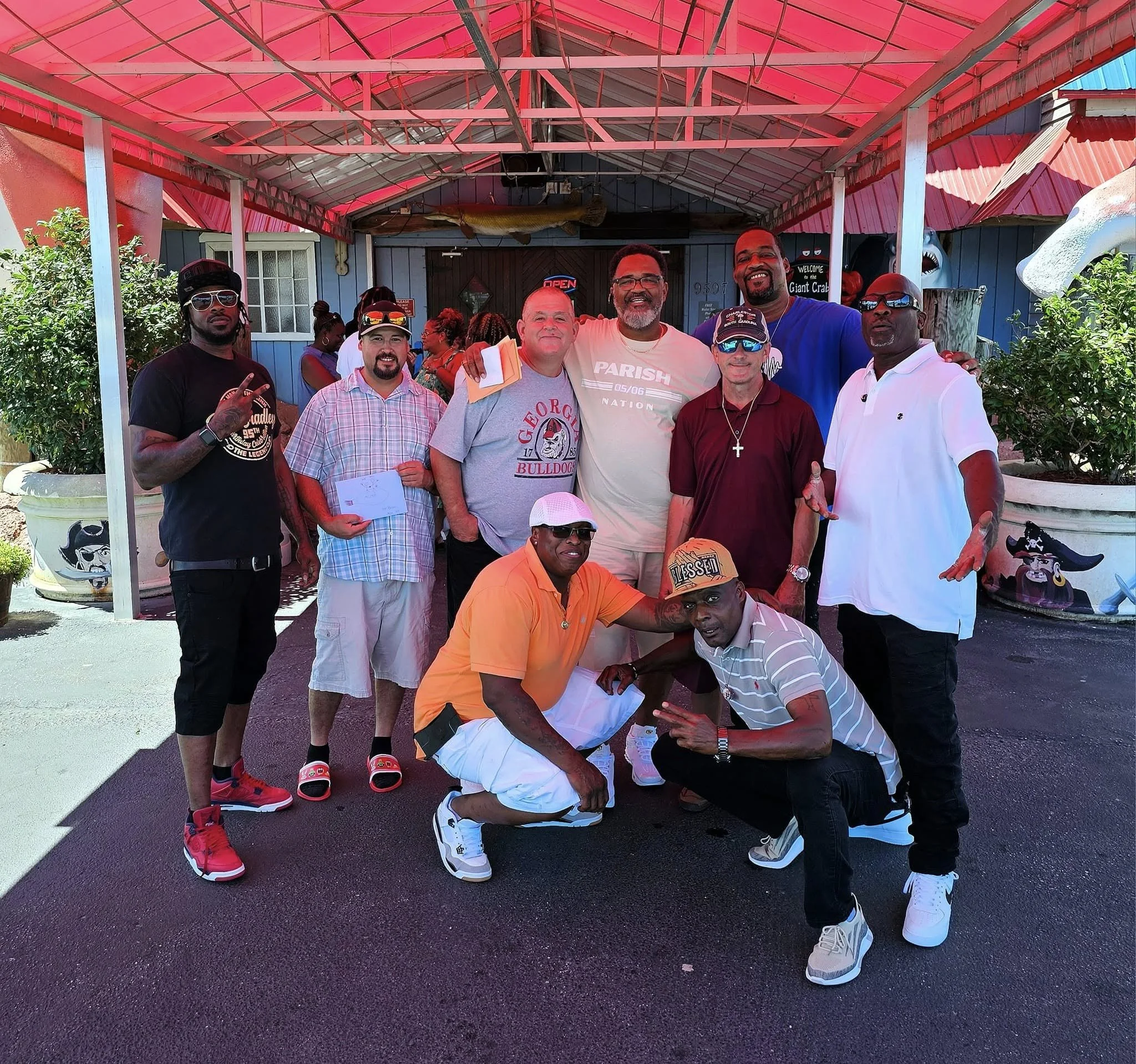 Construction workers repairing or remodeling a house, with one worker on a ladder and others working on the ground.