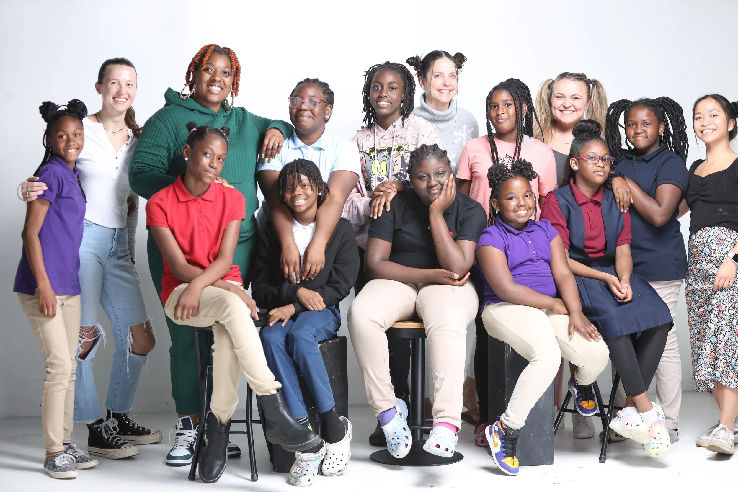 Group of diverse children and adults posing together in a studio setting, smiling for a photo.