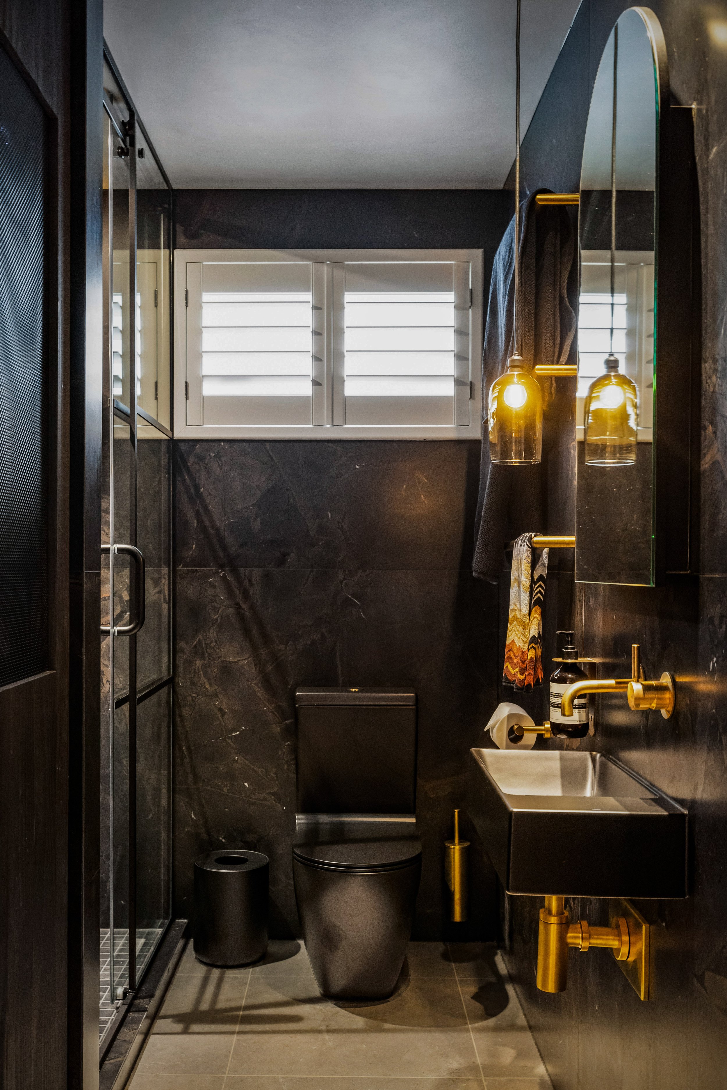 A former laundry room has been transformed into an elegant guest bathroom while also discreetly incorporating a stylish laundry area.