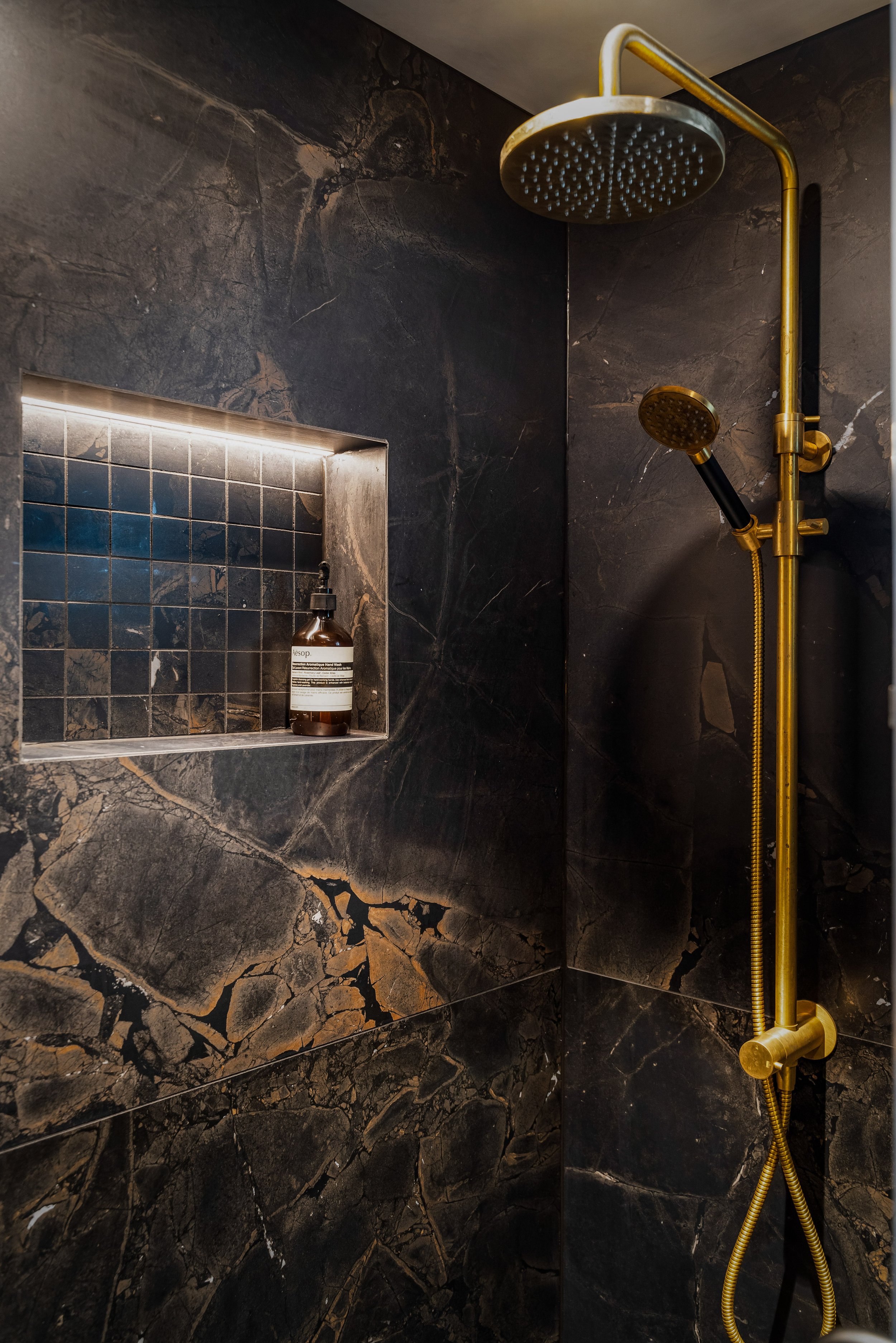 The fusion of dramatic Brazilian wall tiles and mosaics creates a harmonious balance with the aged brass Progetto showerhead.