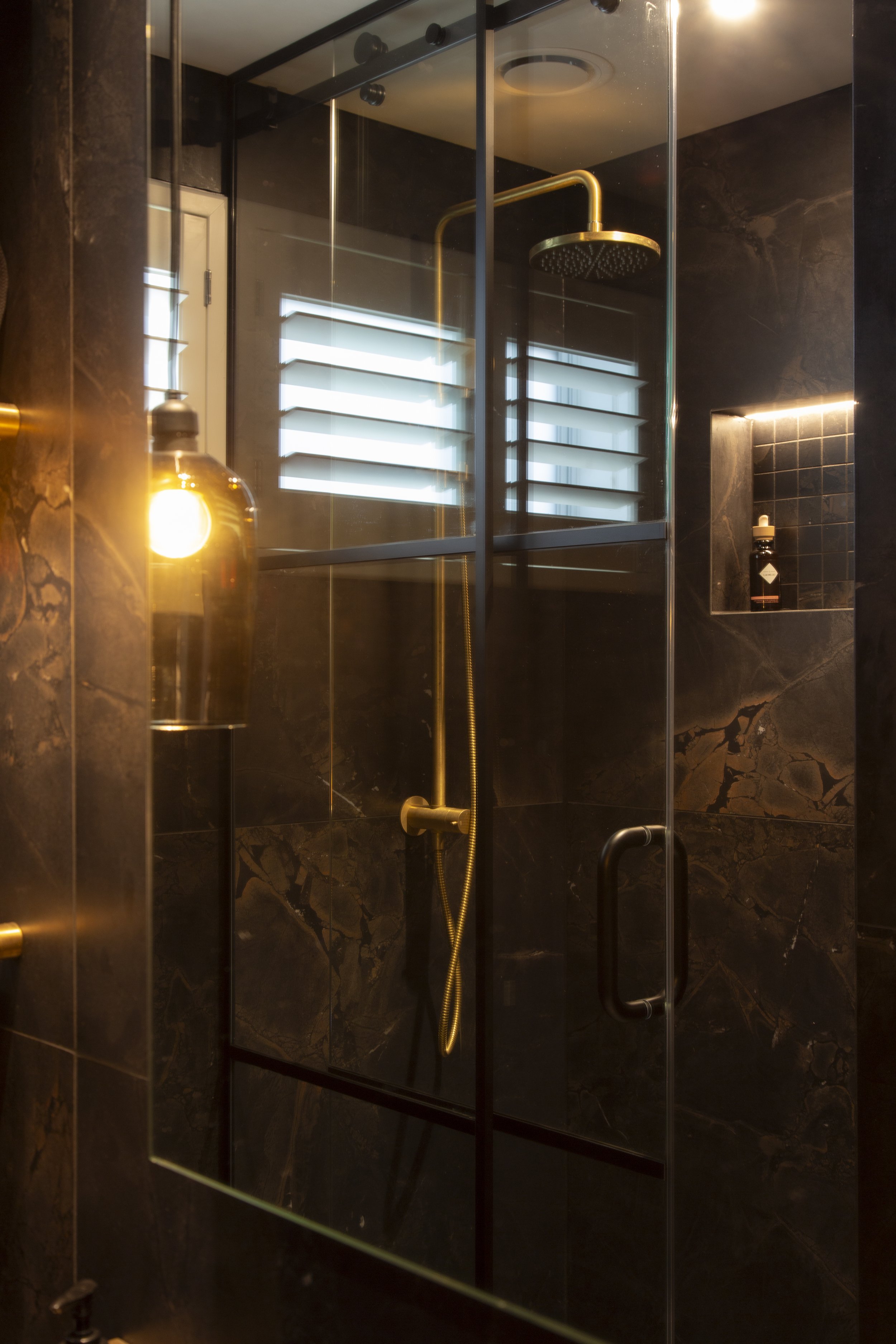 The arched wall vanity unit maintains a minimalist aesthetic in this modern, moody bathroom.