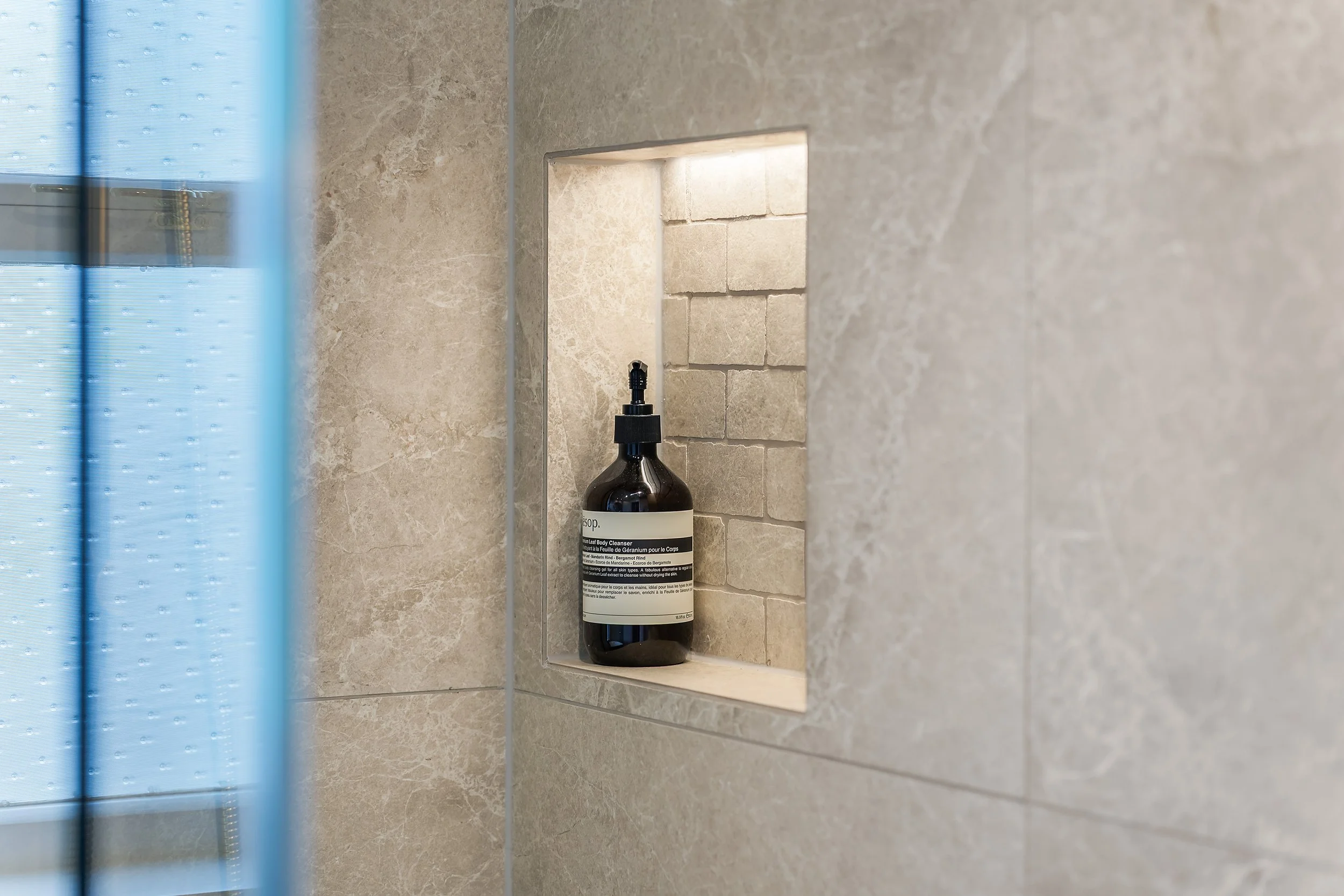 Enter a spa-like retreat where details shine. The simple yet beautiful combination of beige, sand-colored tiles and mosaics is highlighted inside the shower niche by sensor-activated strip lighting, creating a stunning focal point.