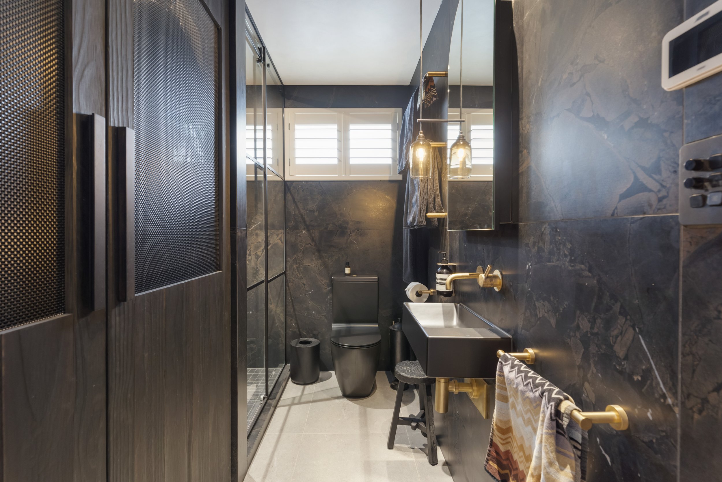 A former laundry room has been transformed into an elegant guest bathroom while also discreetly incorporating a stylish laundry area.