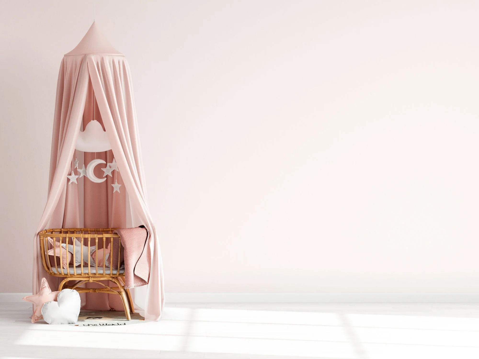 Baby crib with pink canopy, hanging stars, moon, and clouds decor, white wall background, white floor.