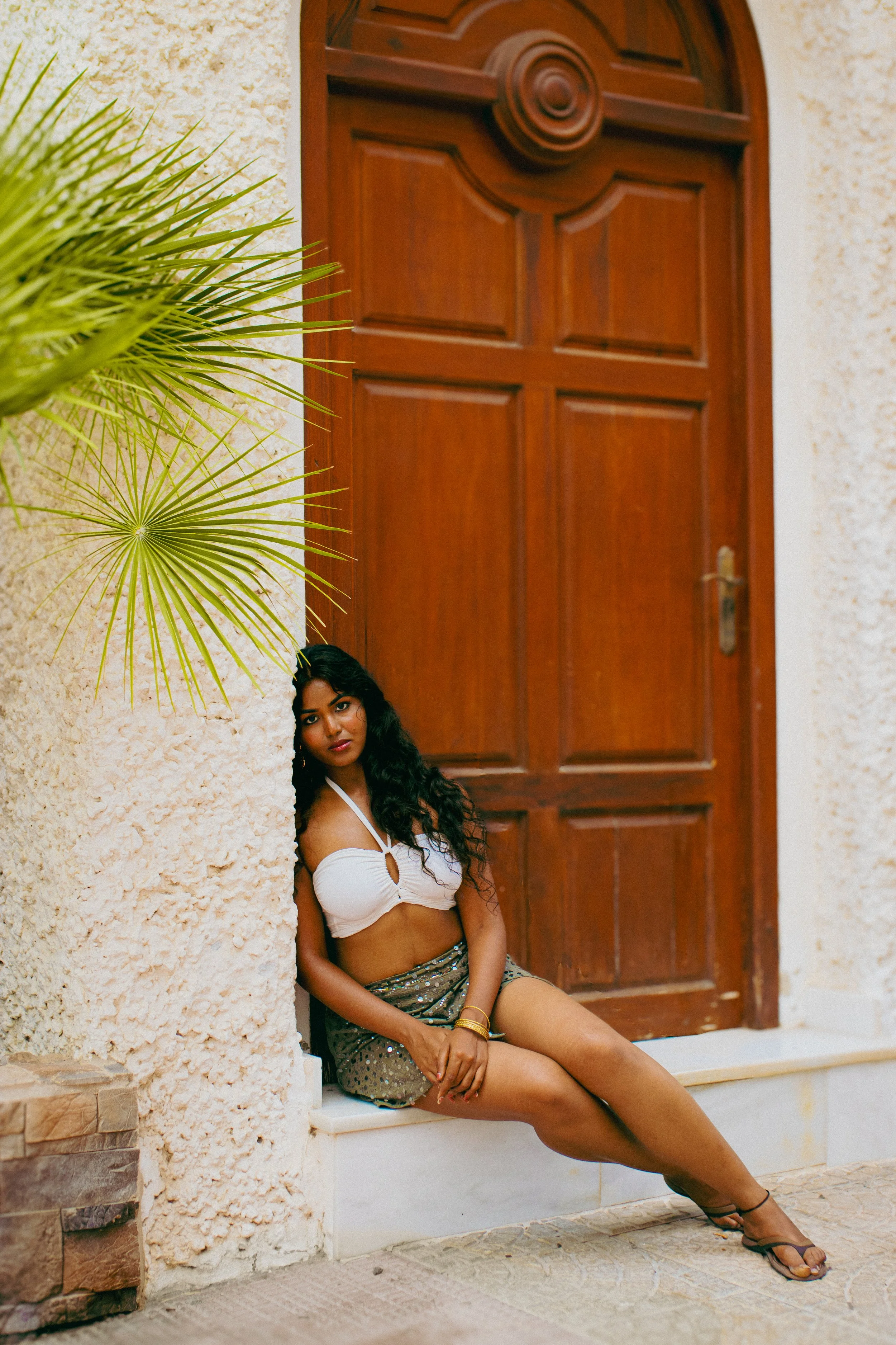 Priya Veda Pathak portrait photographer Priya V. Photography capturing South Asian female model in small Spanish town, posing against wooden door. 