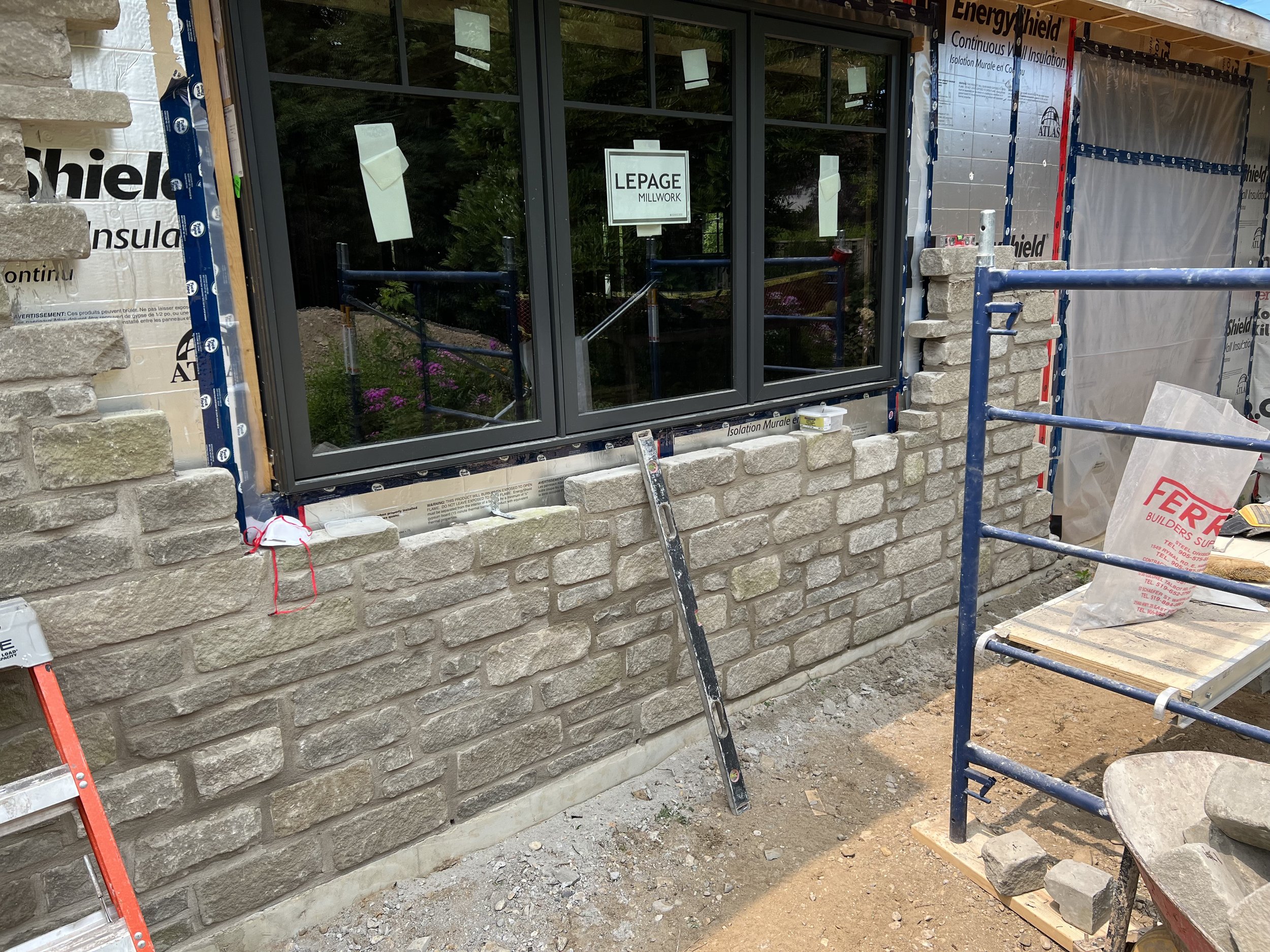 Construction site with stone brick wall in progress and window installation.