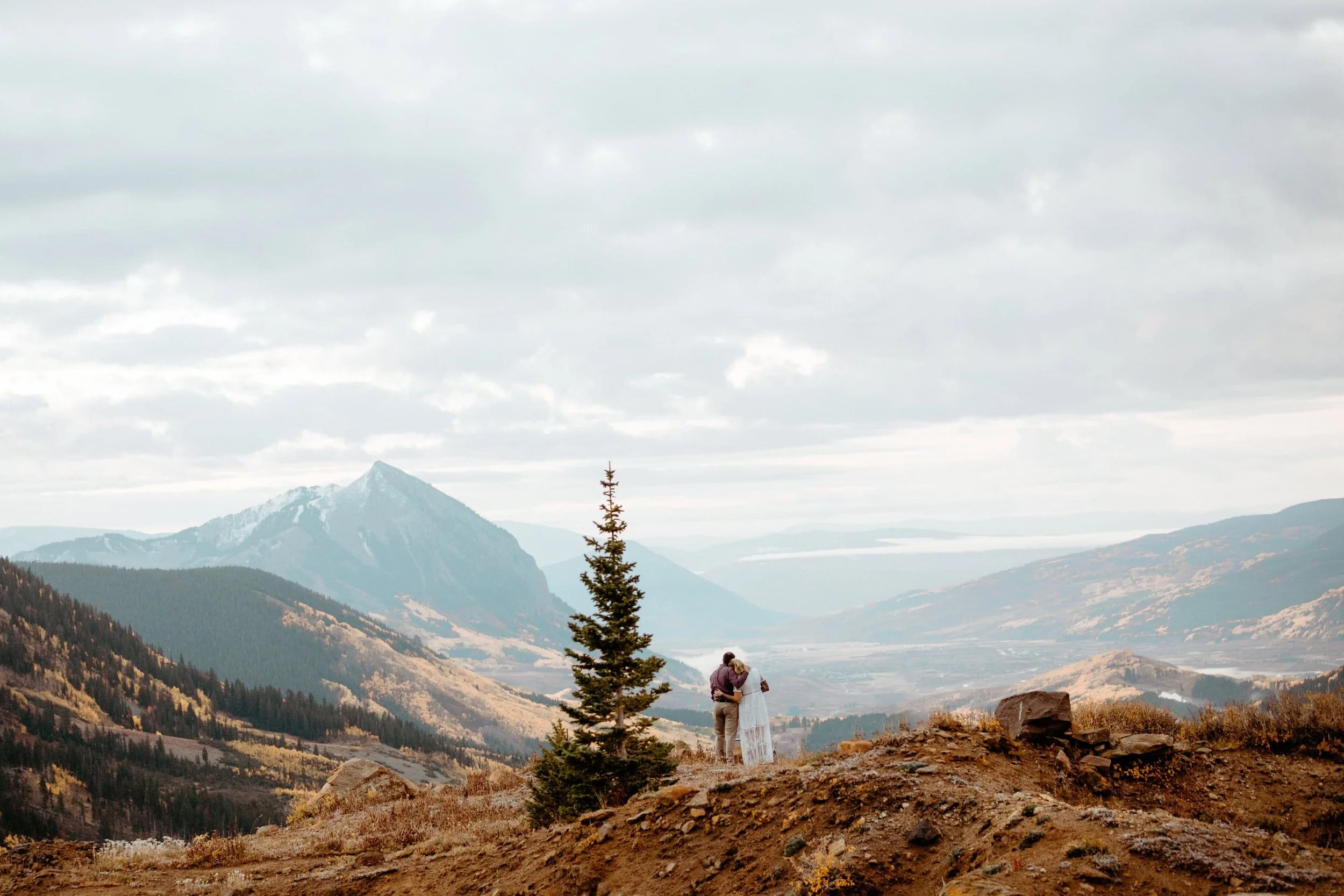 A couple stands on a hilltop outside of Crested Butte after getting married during sunrise in the fall