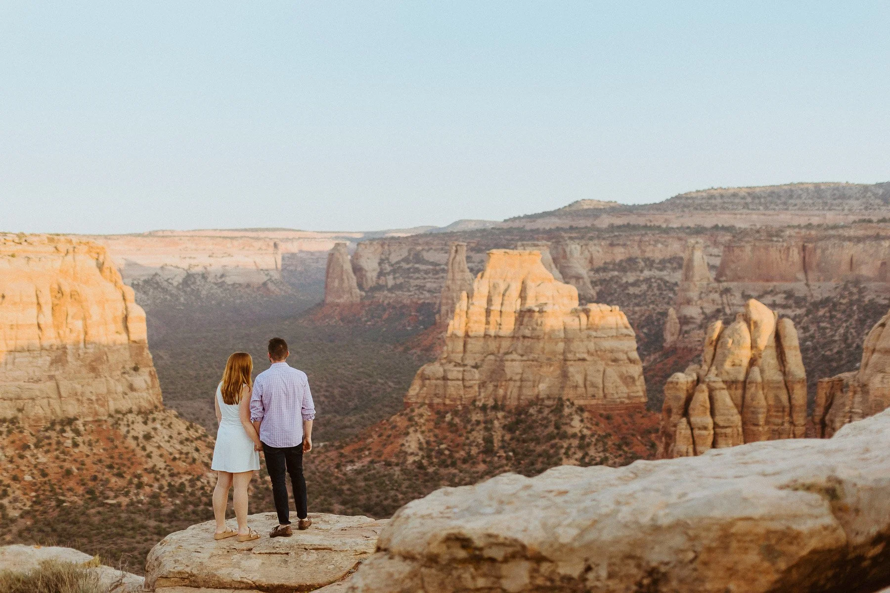 Couple on a rock formation overlooking dramatic canyon views at Colorado National Monument near Grand Junction