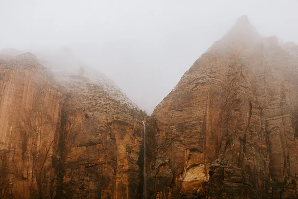 Tall sandstone cliffs shrouded in mist