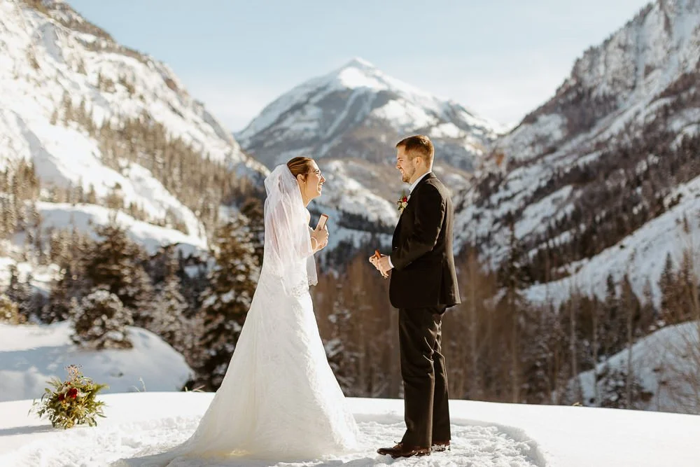 A couple reads vows in front of a snow mountain peak off of the million dollar highway