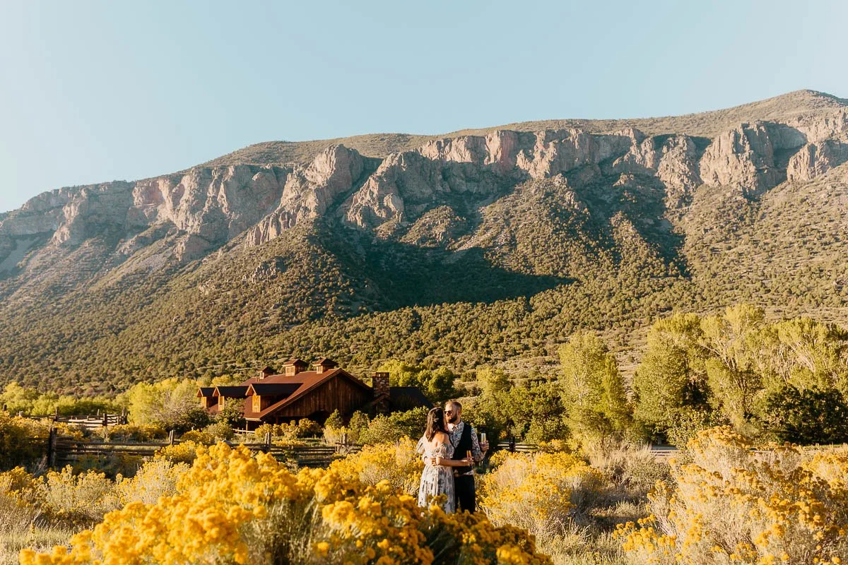 Couple standing in a field of yellow wildflowers near Gateway, Colorado with red rock mountains