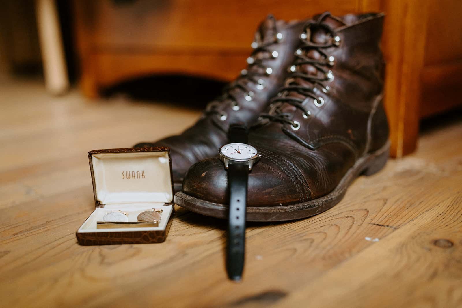 a watch sits on a pair of boots next to cufflinks for getting ready wedding photos