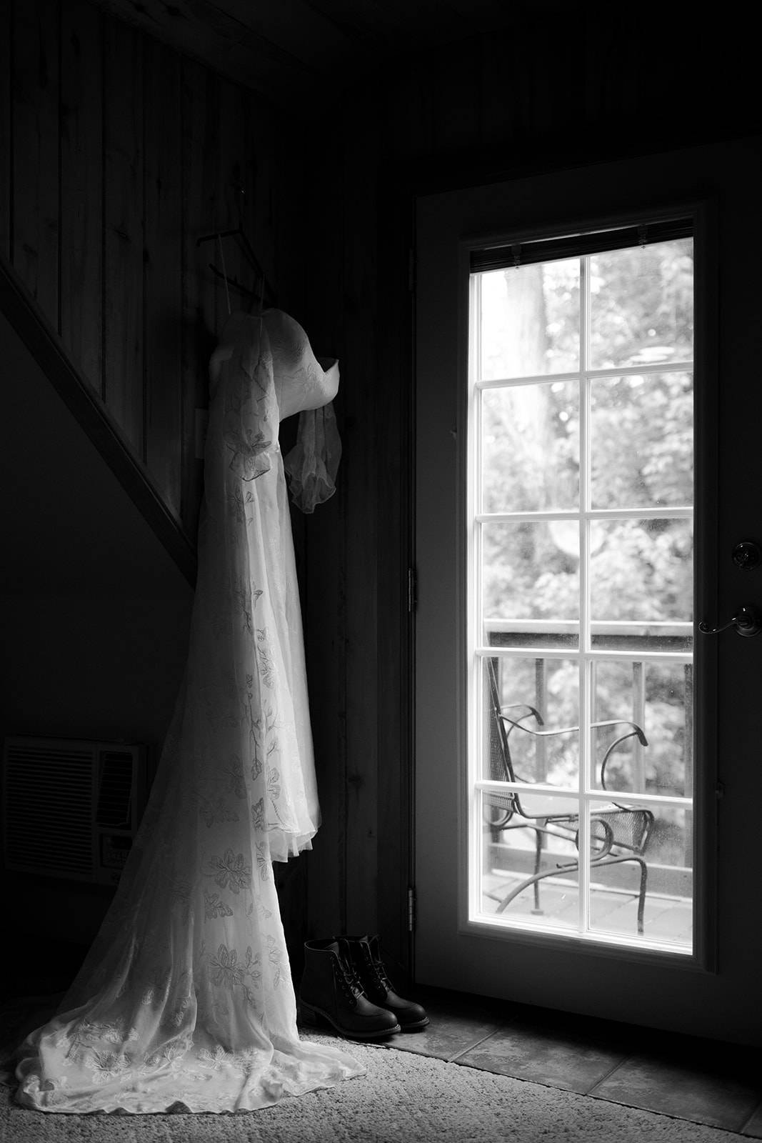 a white wedding dress hangs next to a window at a cabin in the san Juans