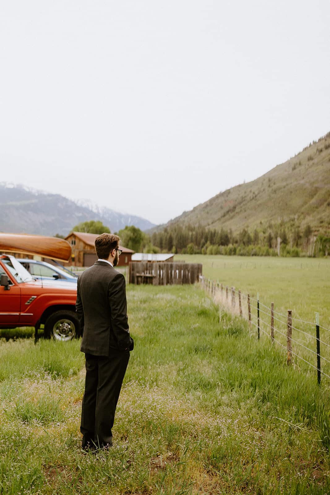 A man stands facing away during a first look in front of his Land Cruiser and the San Juan mountains