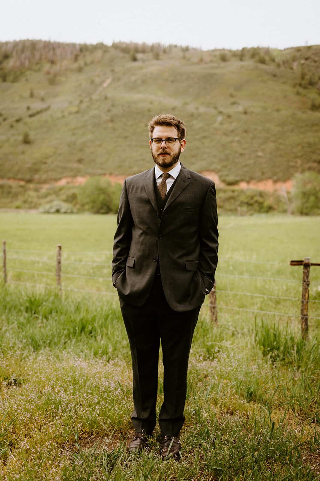 A man faces forward in a suit in a field in Colorado